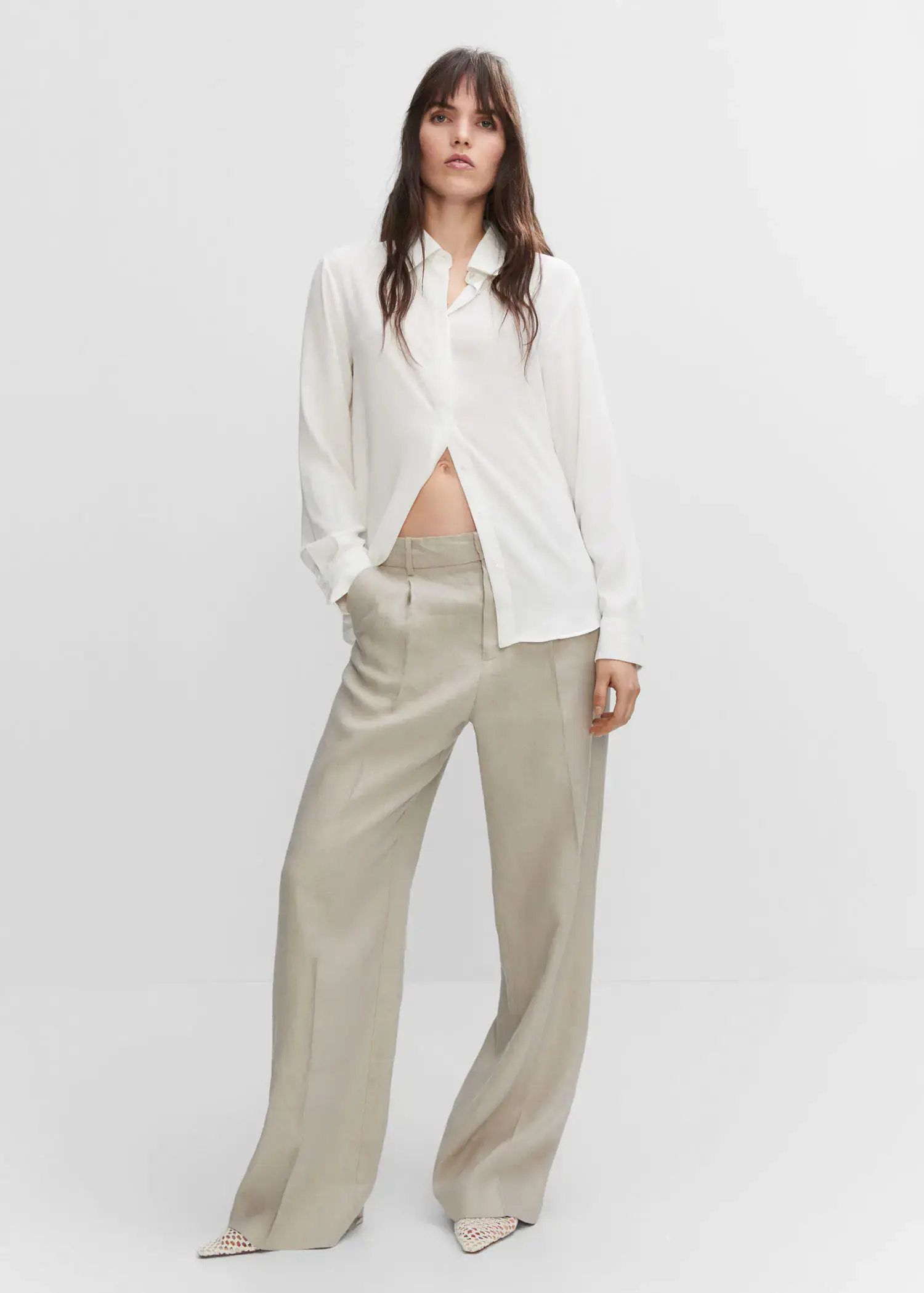 Mango Buttoned flowy shirt. a woman in a white shirt and beige pants. 