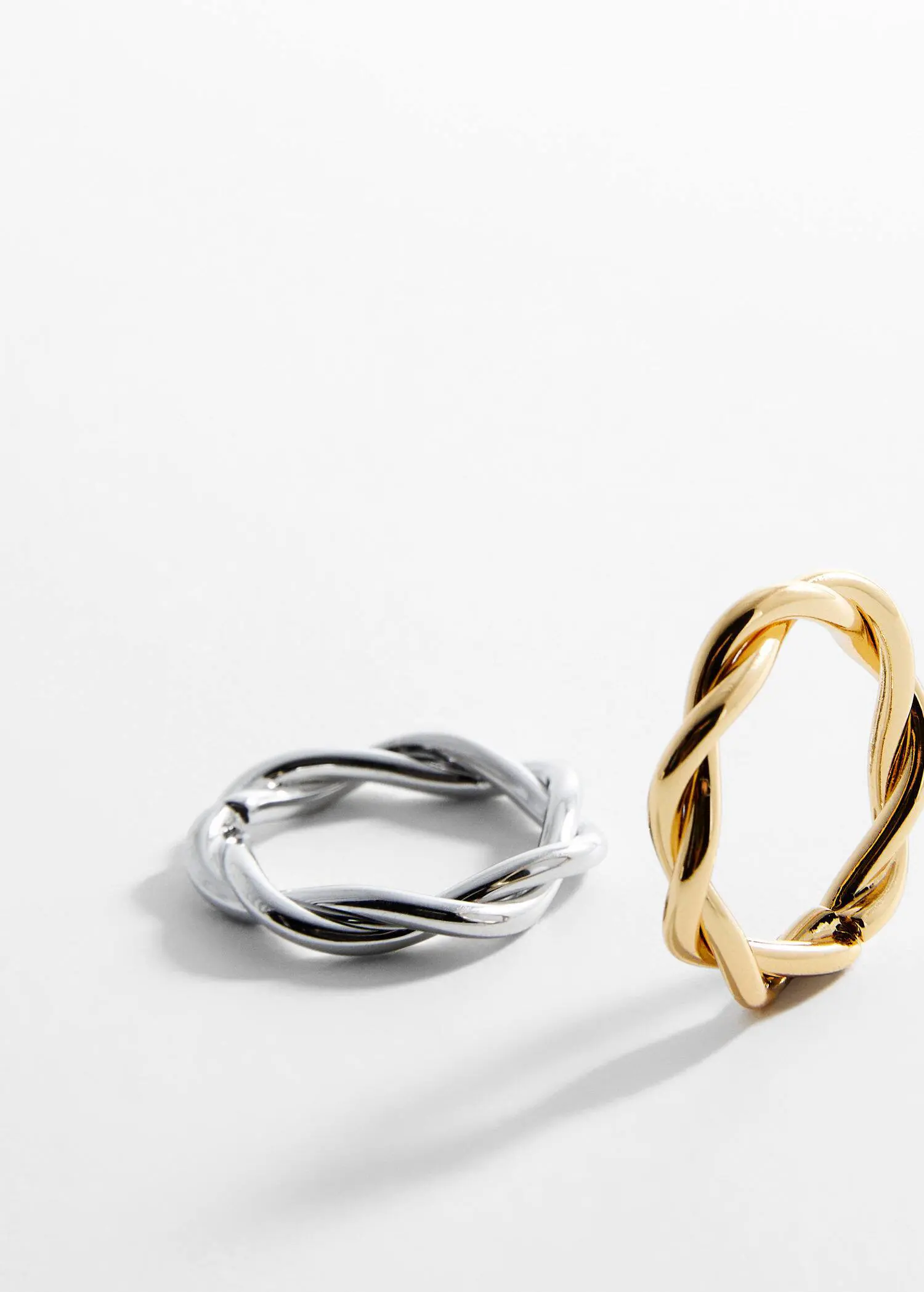 Mango Criss-cross 2 ring set. a pair of gold and silver rings sitting next to each other. 