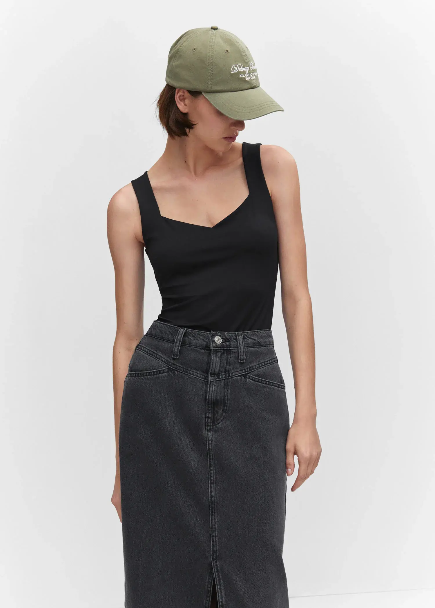 Mango Open elastic top. a woman wearing a black tank top and a hat. 