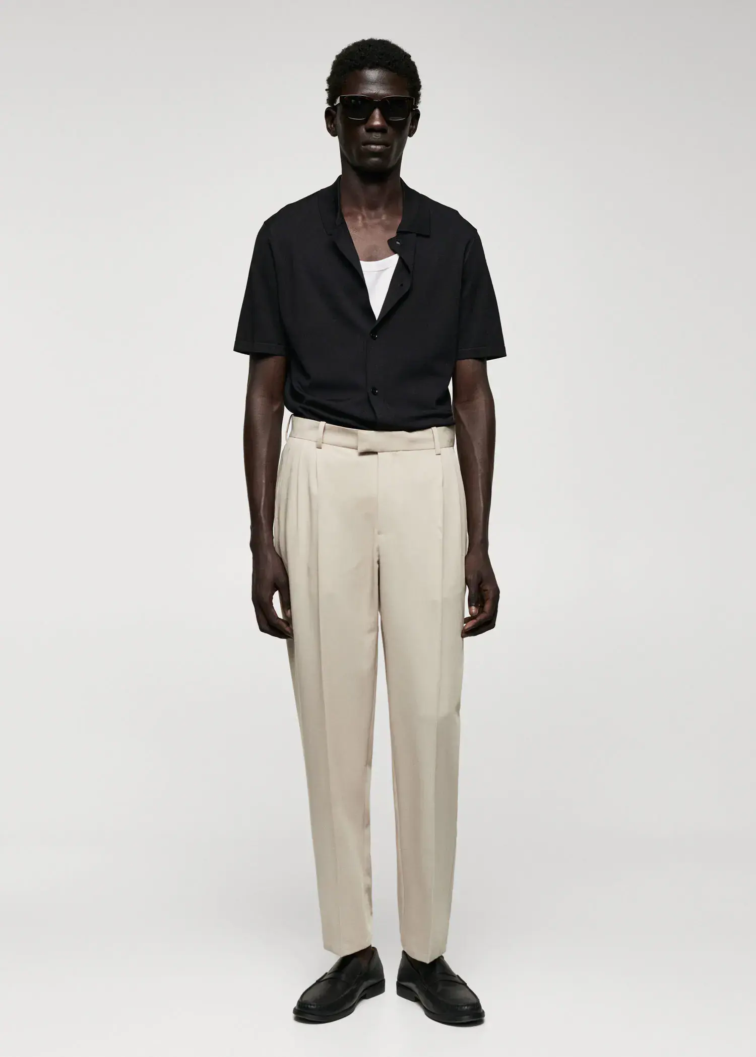 Mango Regular-fit suit pants with pleats. a man standing in front of a white wall. 