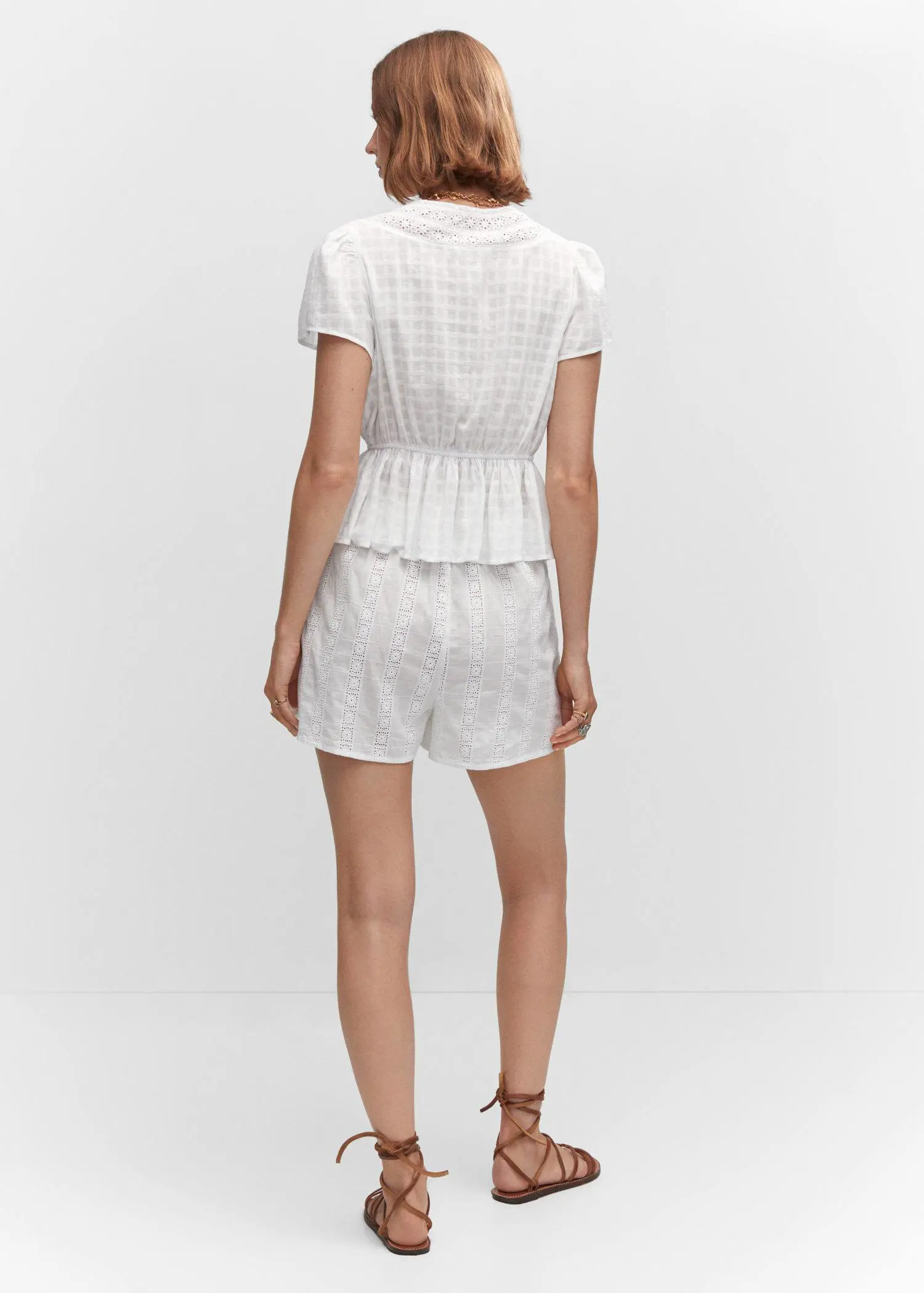 Mango Embroidered openwork blouse. a person wearing a white outfit standing in a room. 