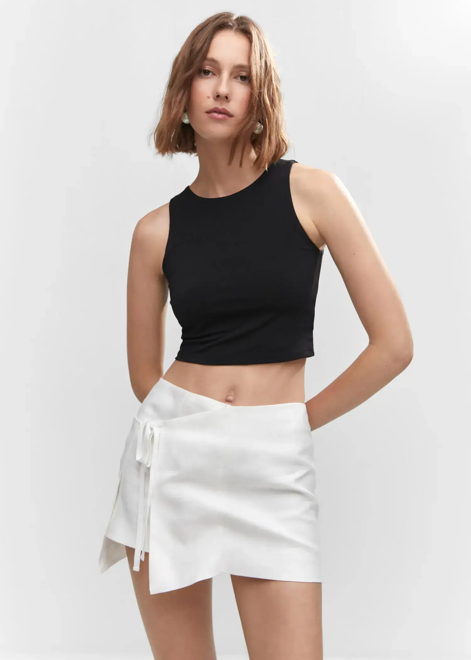 Mango Crop top halter neck. a woman wearing a black crop top and a white skirt. 