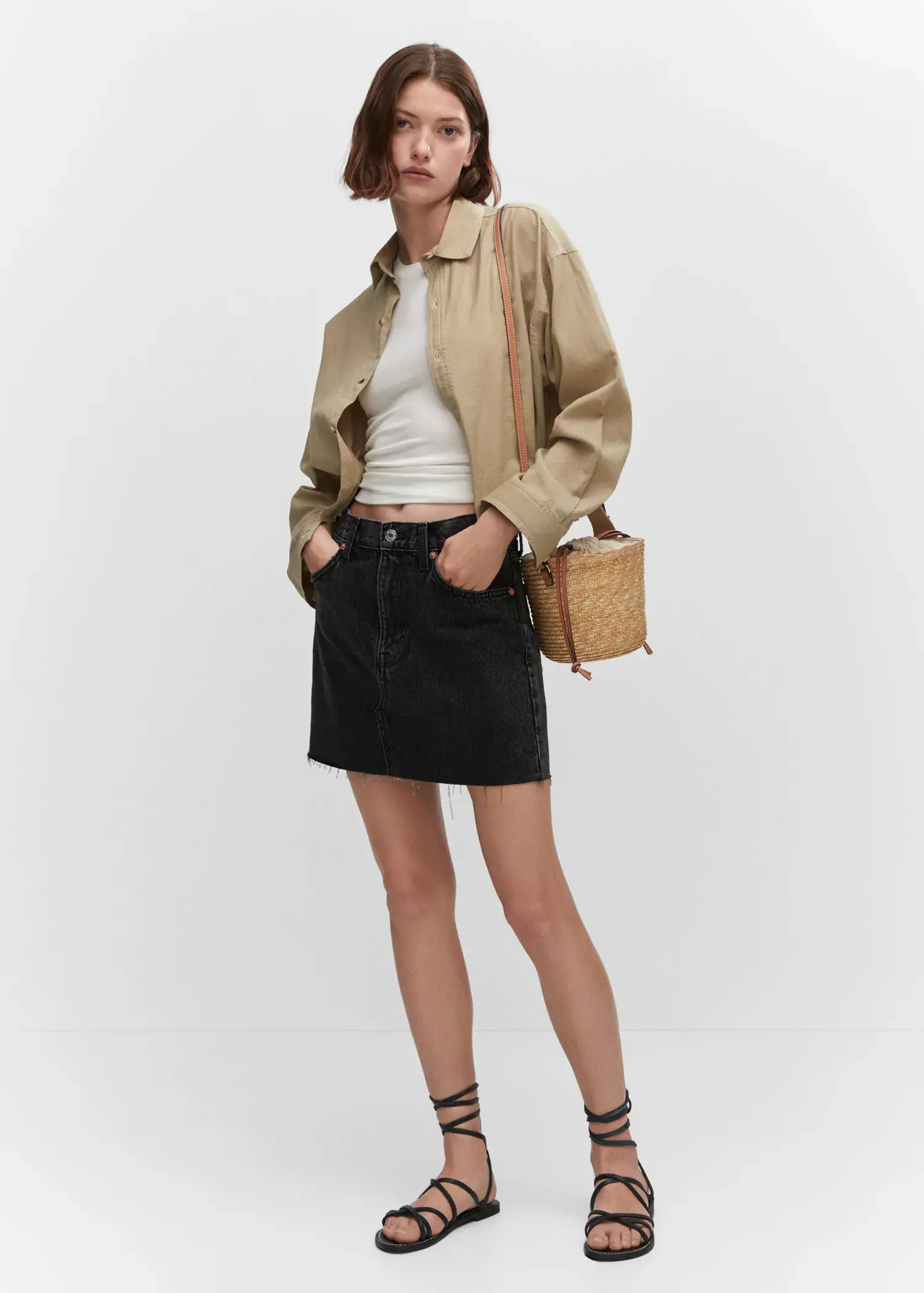 Mango Denim mini-skirt. a woman in a tan jacket and black skirt holding a purse. 