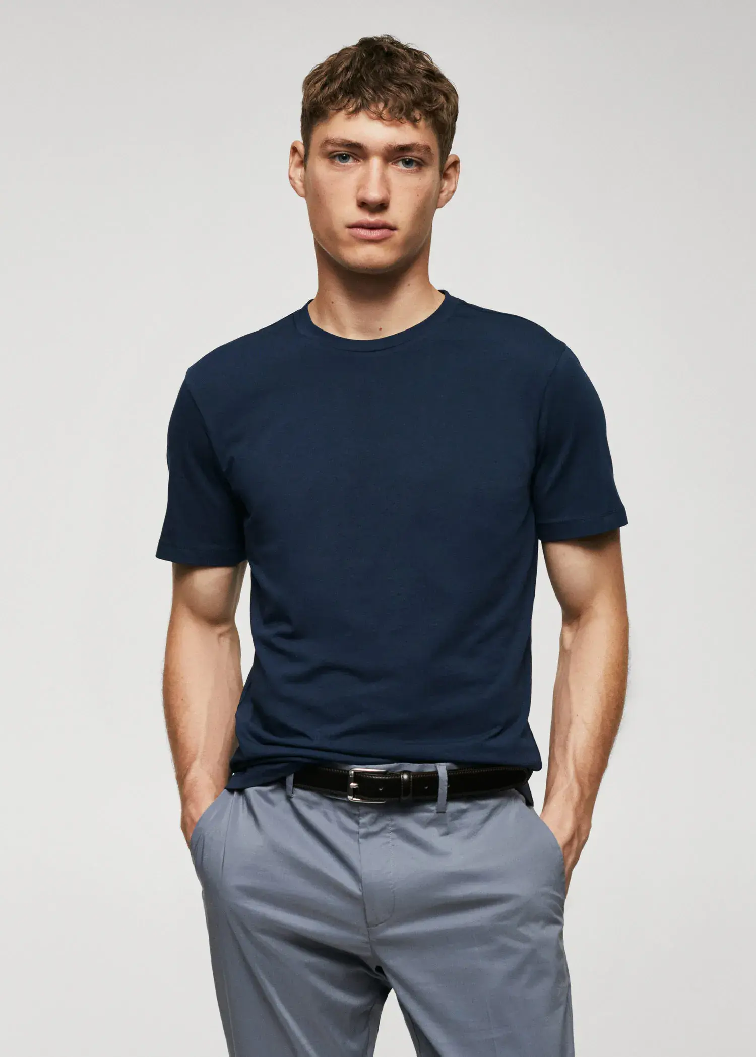 Mango Basic lightweight cotton t-shirt. a man in a blue shirt is standing with his hands in his pockets 