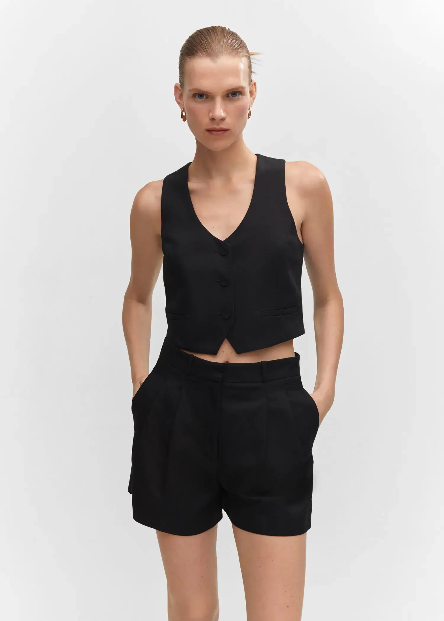 Mango Fitted vest with buttons. a woman wearing a black top and black shorts. 