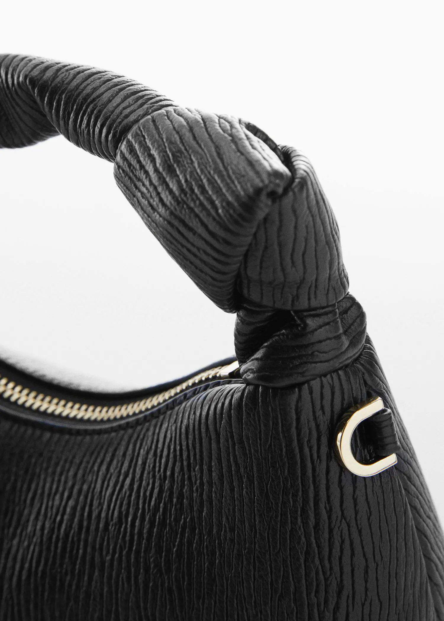 Mango Textured knot handle bag. a close-up view of the handle of a black handbag. 