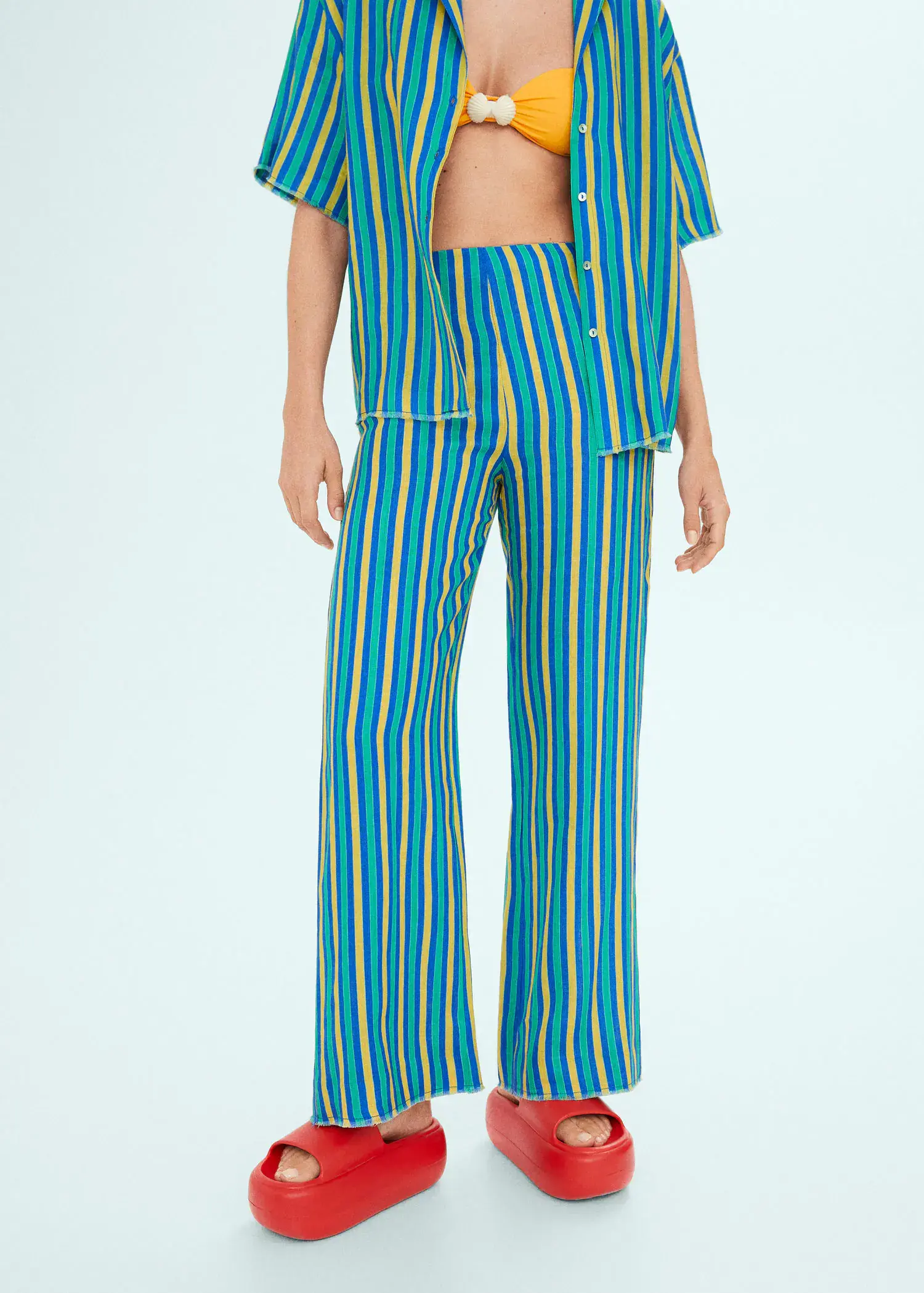 Mango Multi-colored striped linen pants. a person standing in a room wearing a blue and yellow striped outfit. 