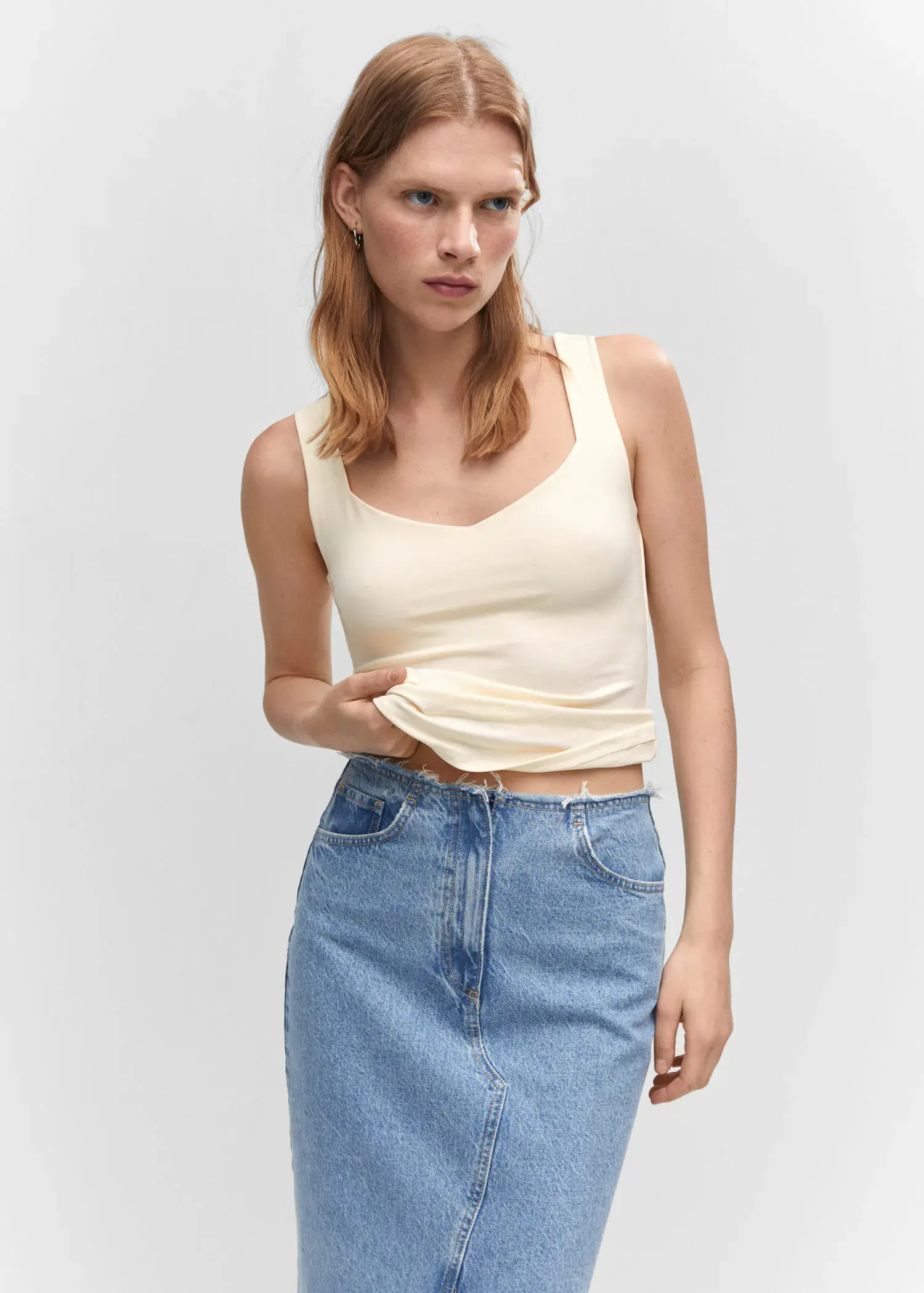 Mango Open elastic top. a woman in a white tank top and blue denim skirt. 