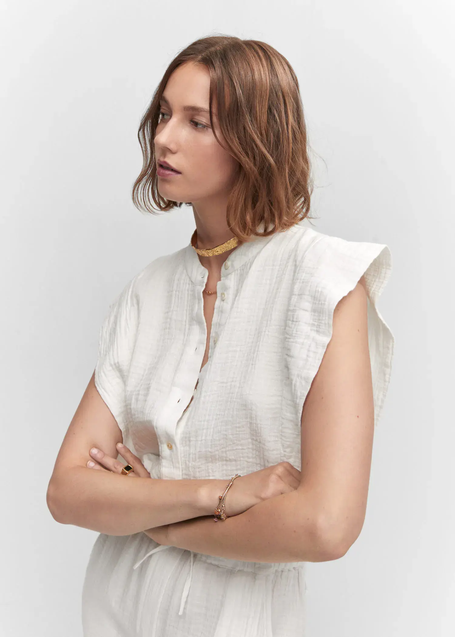 Mango Textured jumpsuit with button. a woman with her arms crossed wearing a white shirt. 