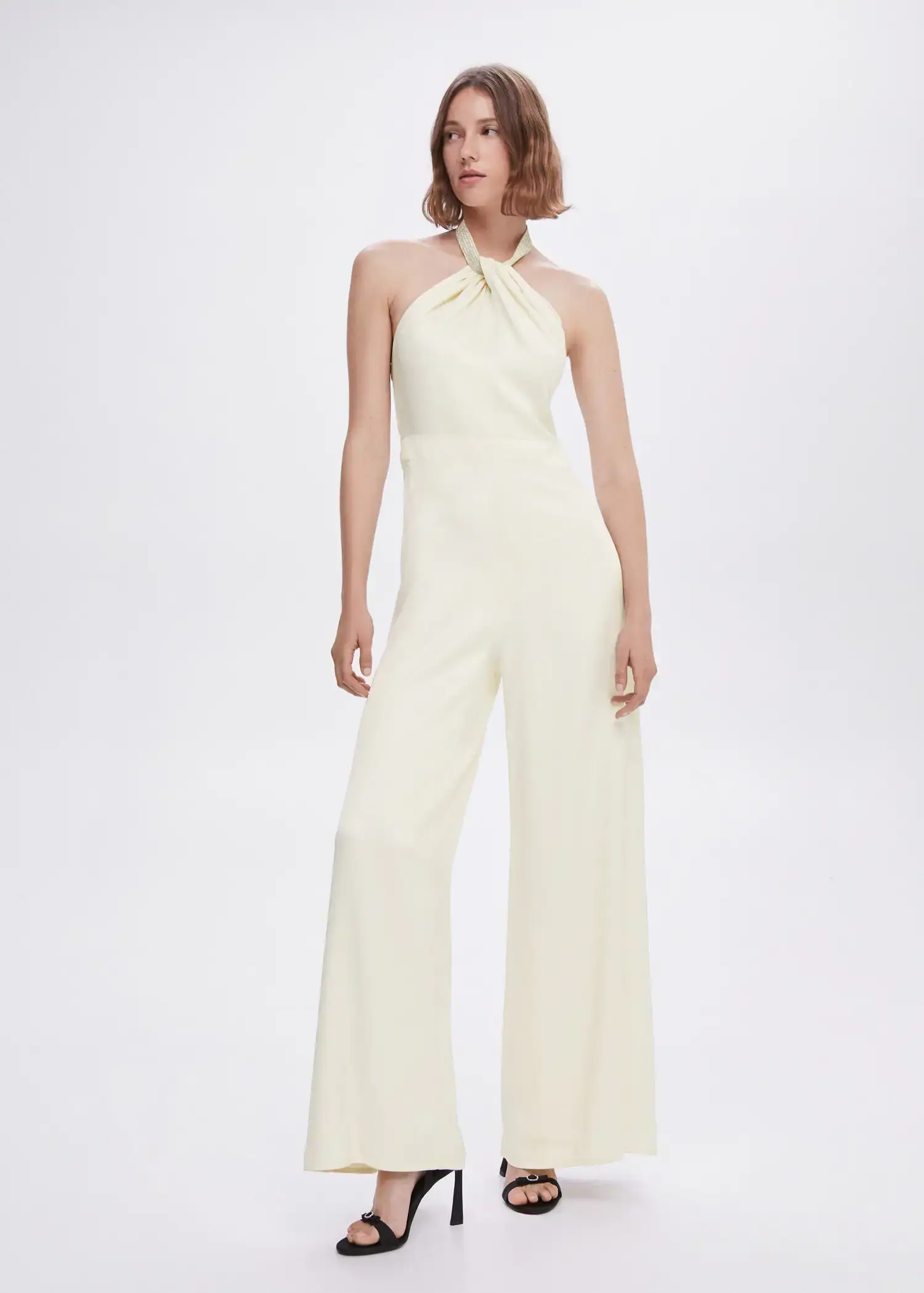 Mango Halter-neck jumpsuit with metallic detail. a woman in a white jumpsuit standing in front of a white wall. 