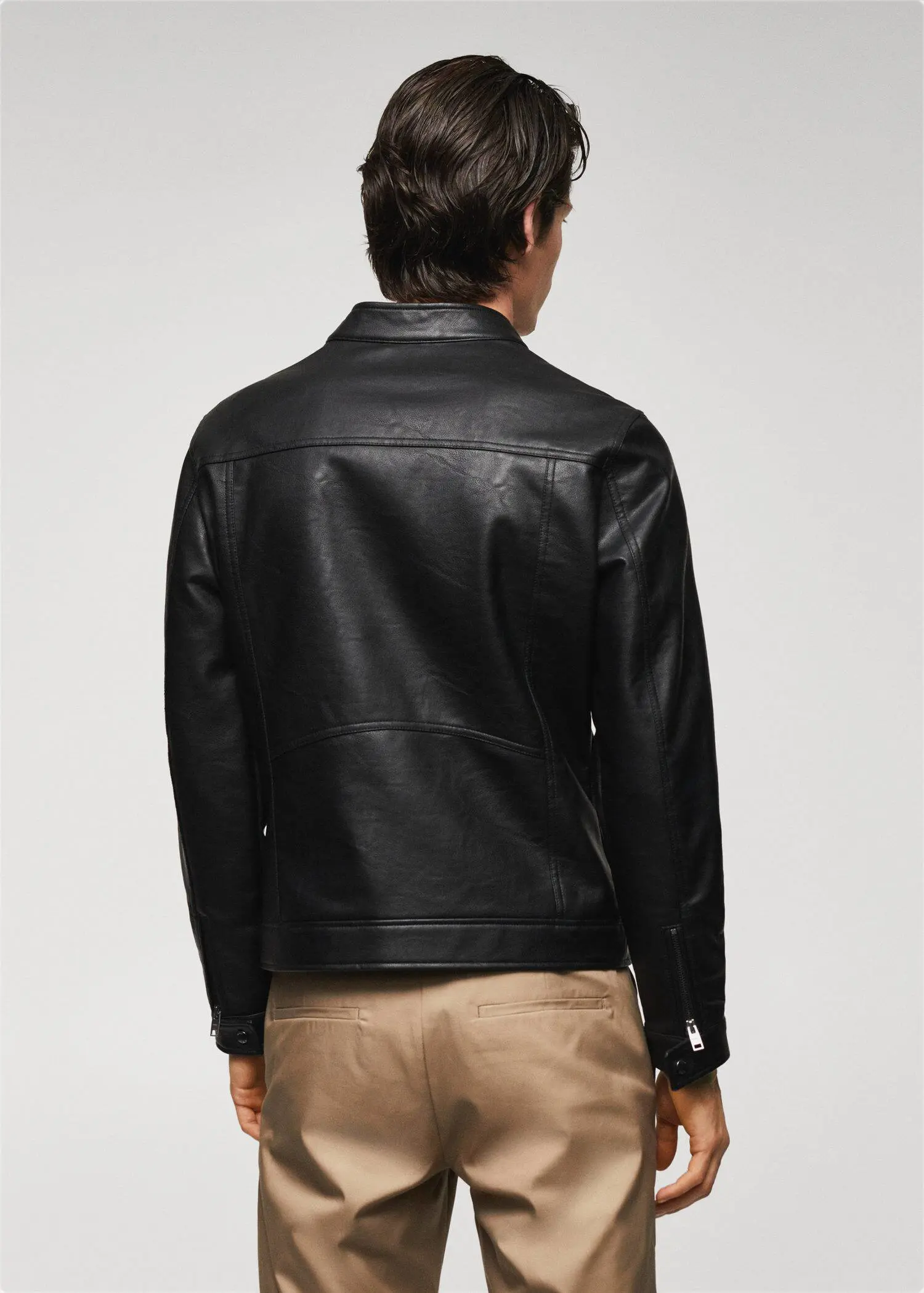 Mango Leather-effect jacket with zips. a man wearing a black leather jacket and brown pants. 