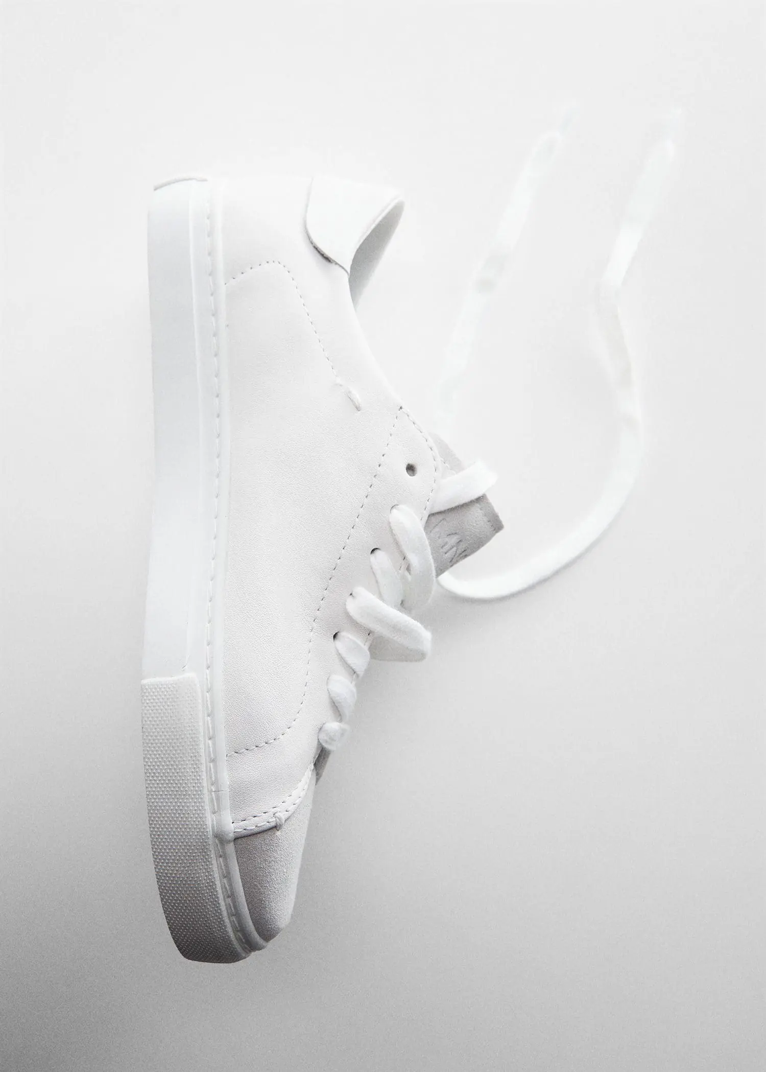 Mango Leather panel sneakers. a pair of white sneakers hanging on a wall. 
