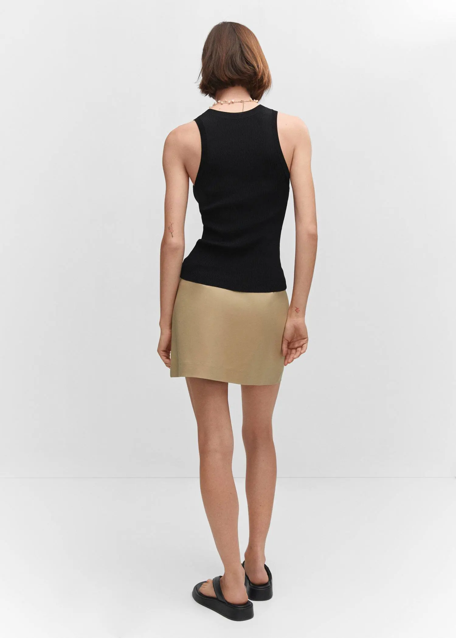 Mango Ribbed knit top. a woman wearing a black top and a tan skirt. 