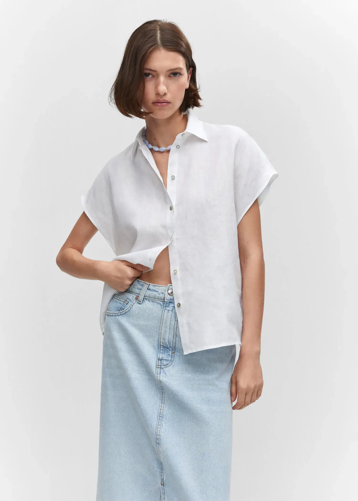 Mango Short sleeve linen-blend shirt. a woman wearing a white shirt and a blue skirt. 