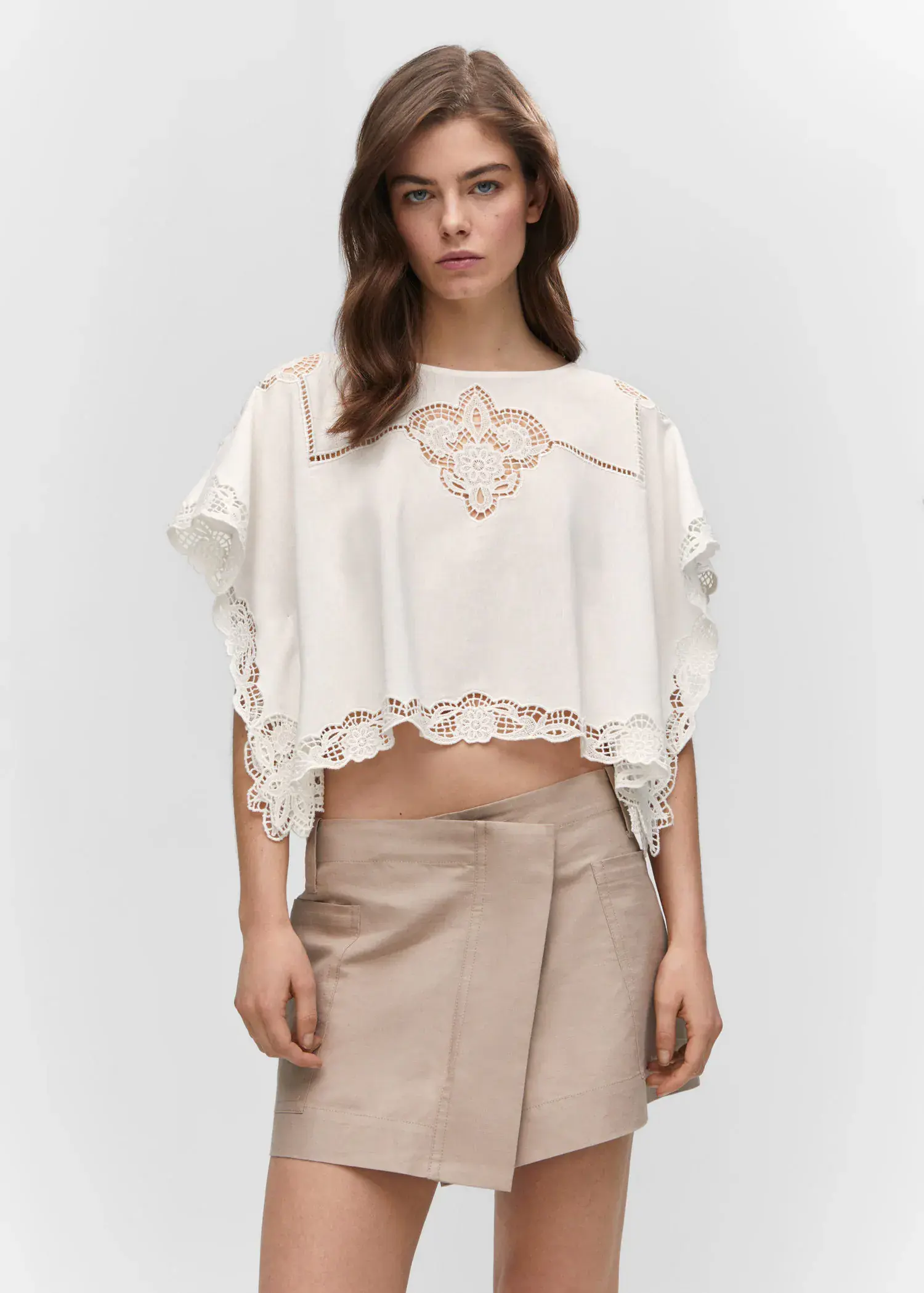 Mango Embroidered openwork blouse. a woman wearing a white top and a beige skirt. 