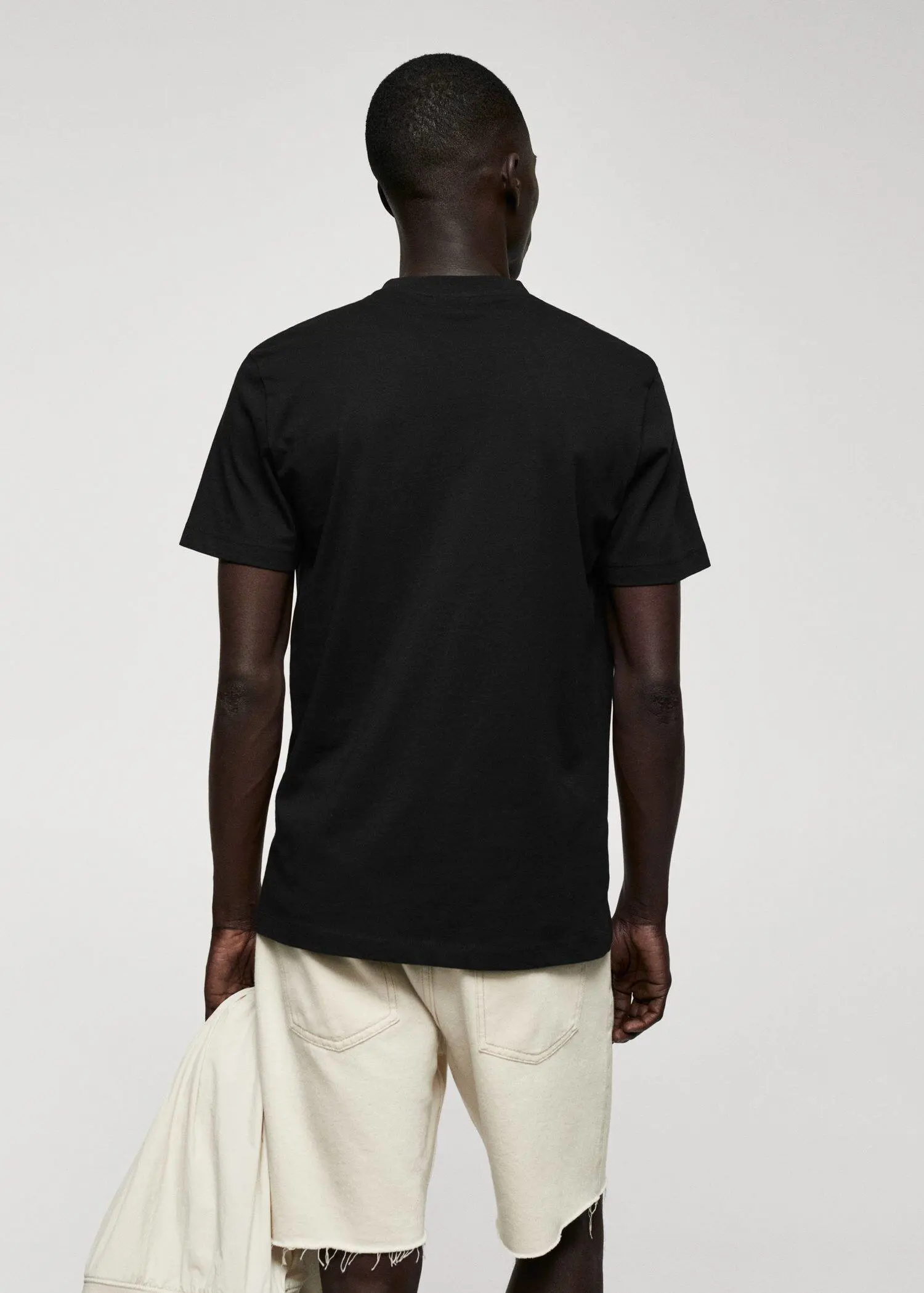 Mango Basic cotton V-neck T-shirt. a person wearing a black t-shirt and white pants. 