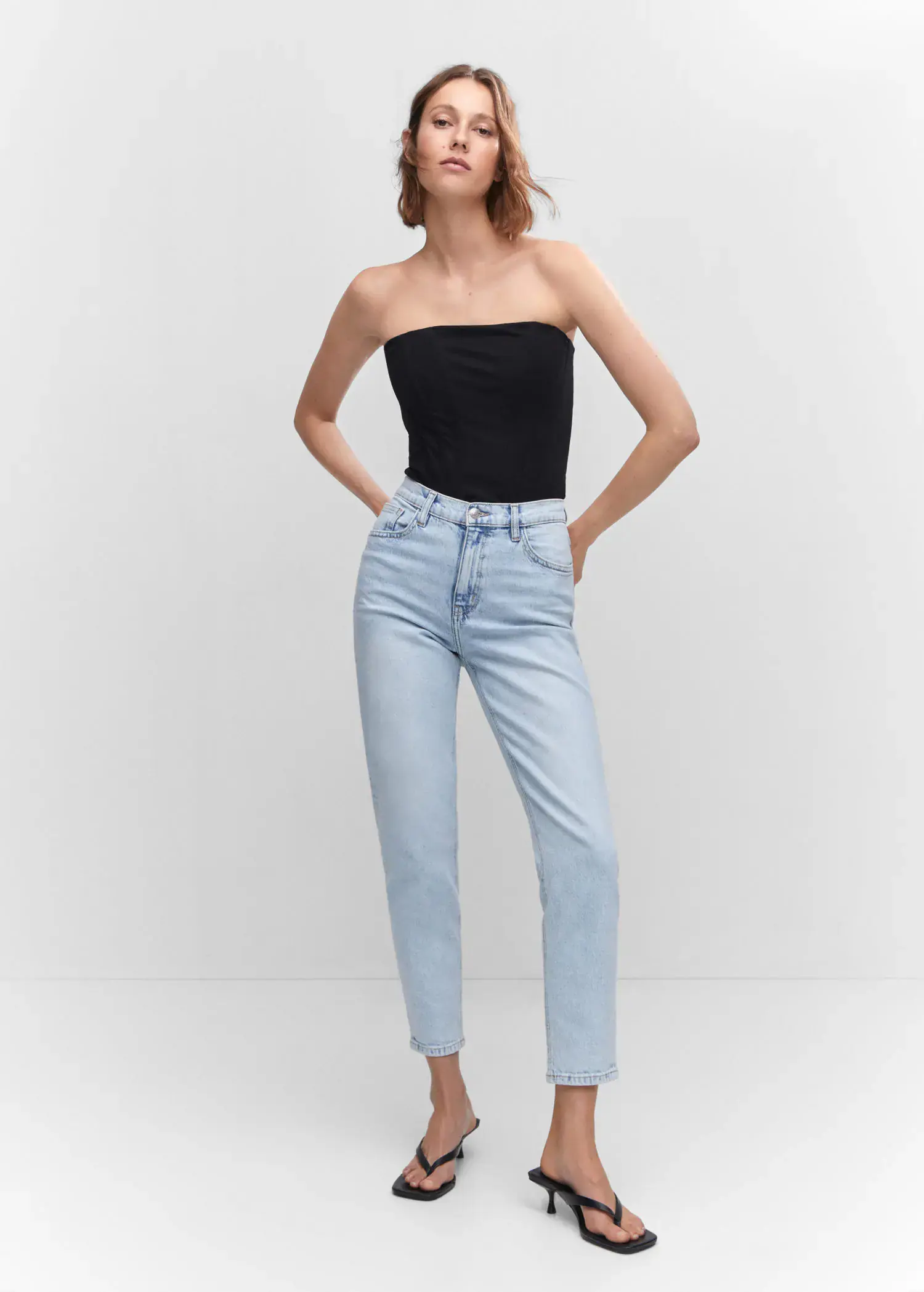 Mango Mom comfort high-rise jeans. a woman in a black top and light blue jeans. 