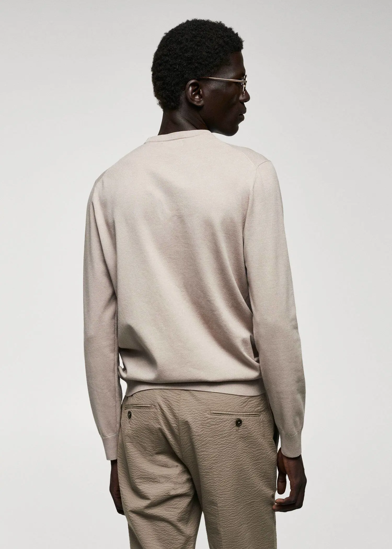 Mango Fine-knit sweater. a man in a beige sweater is standing in front of a wall. 