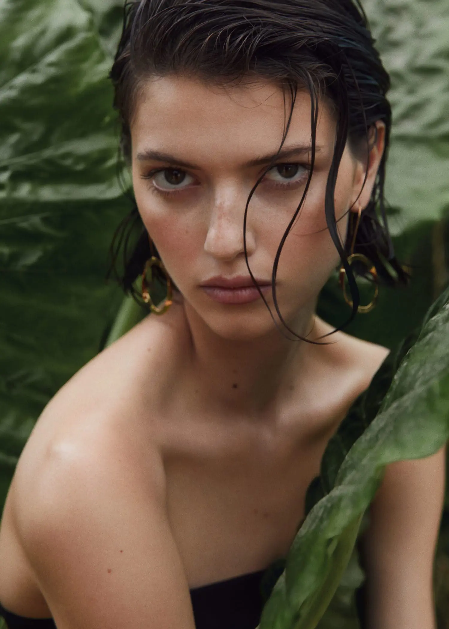 Mango Rigid oval earrings. a beautiful woman with wet hair standing next to a plant. 