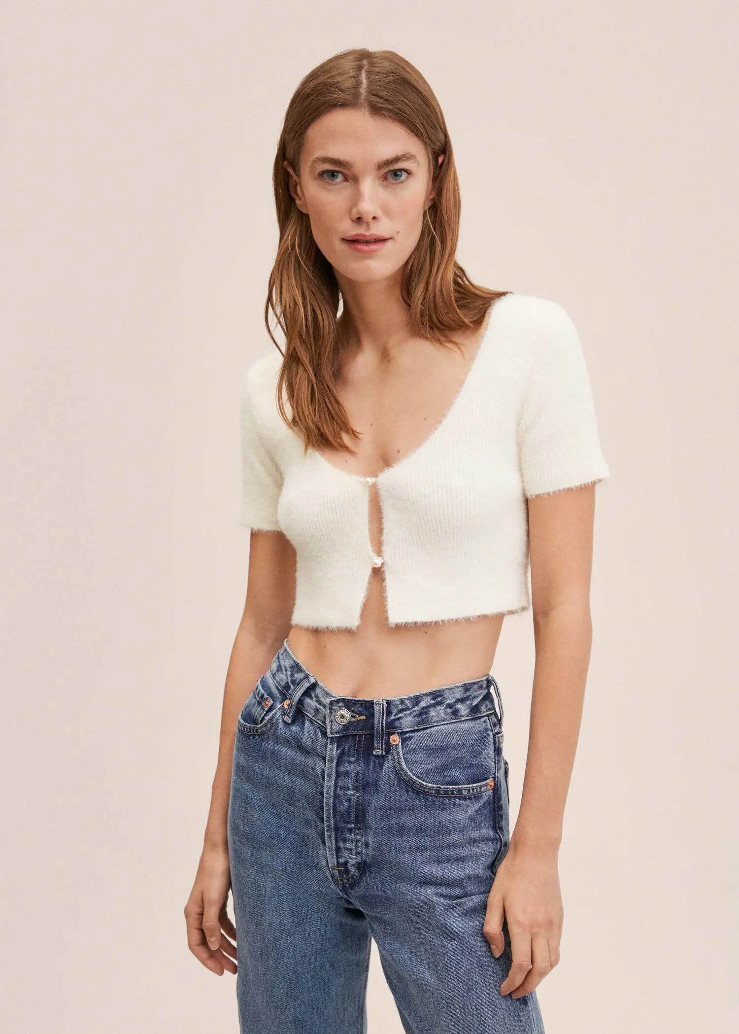 Mango Knitted cropped cardigan. a woman wearing a white crop top and jeans. 