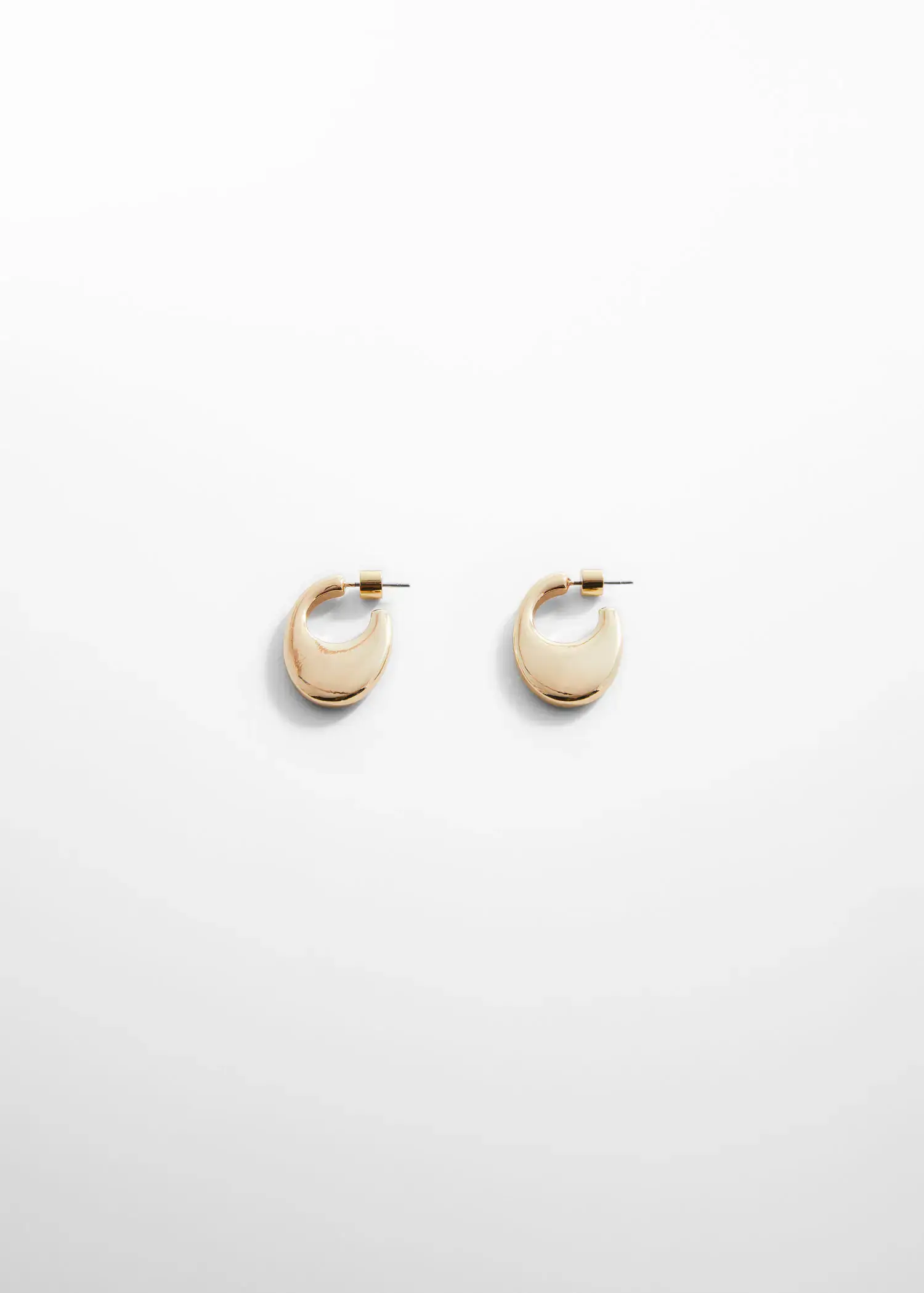 Mango Oval hoop earrings. a pair of earrings on top of a white wall. 