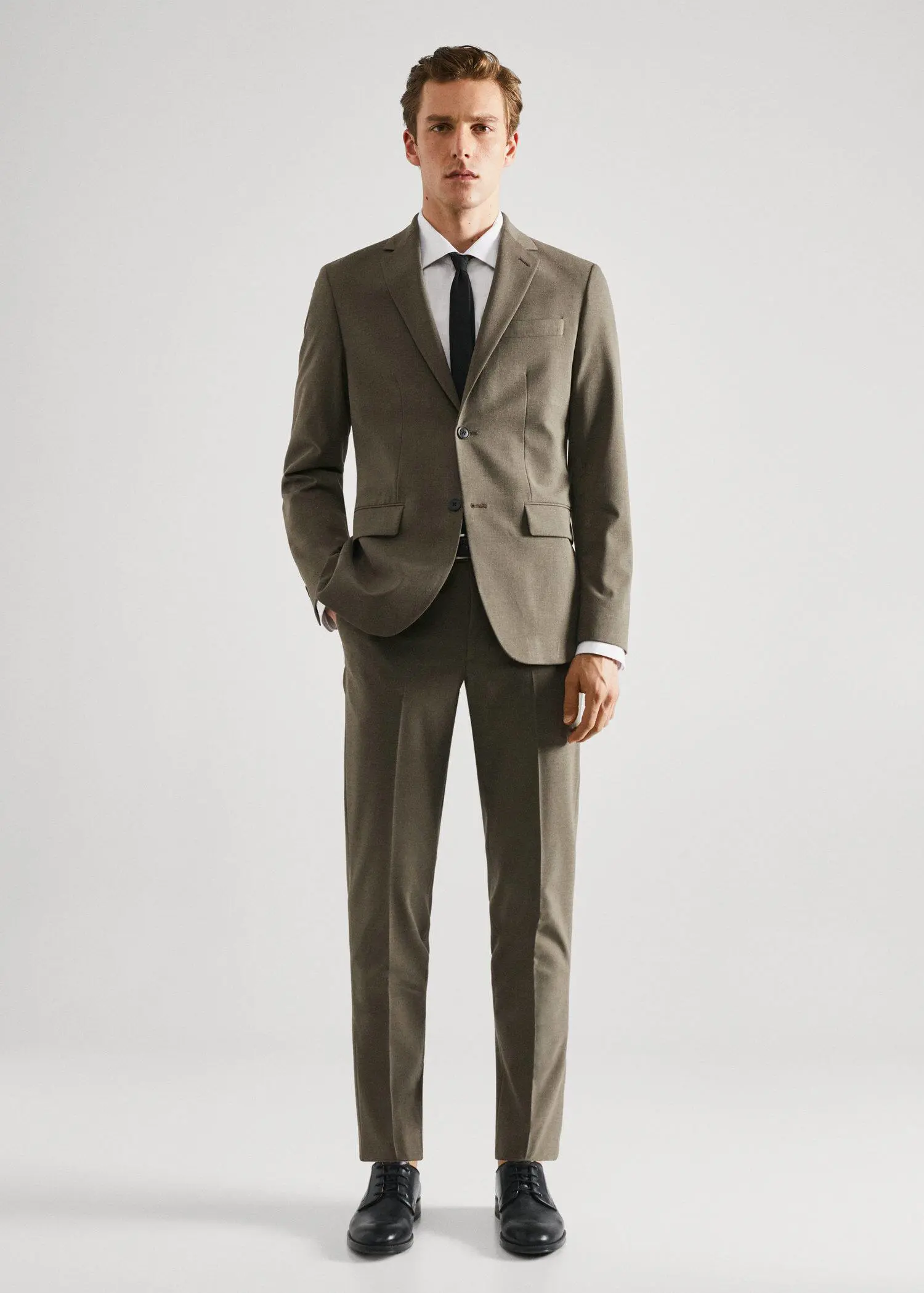 Mango Stretch fabric slim-fit suit blazer. a man in a suit and tie standing in front of a white wall. 
