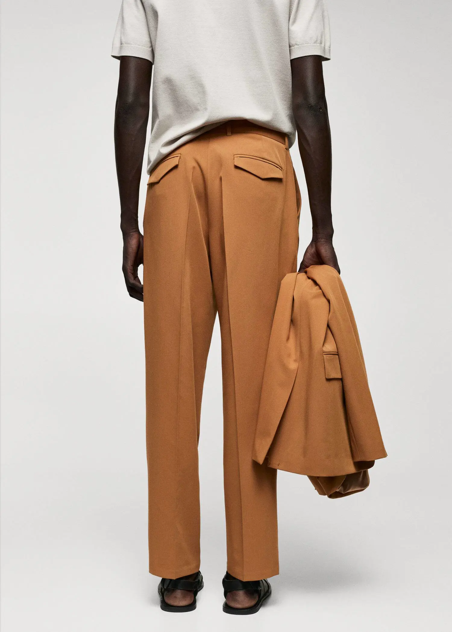 Mango Regular-fit suit trousers with pleats. a man in a tan suit is holding a jacket. 