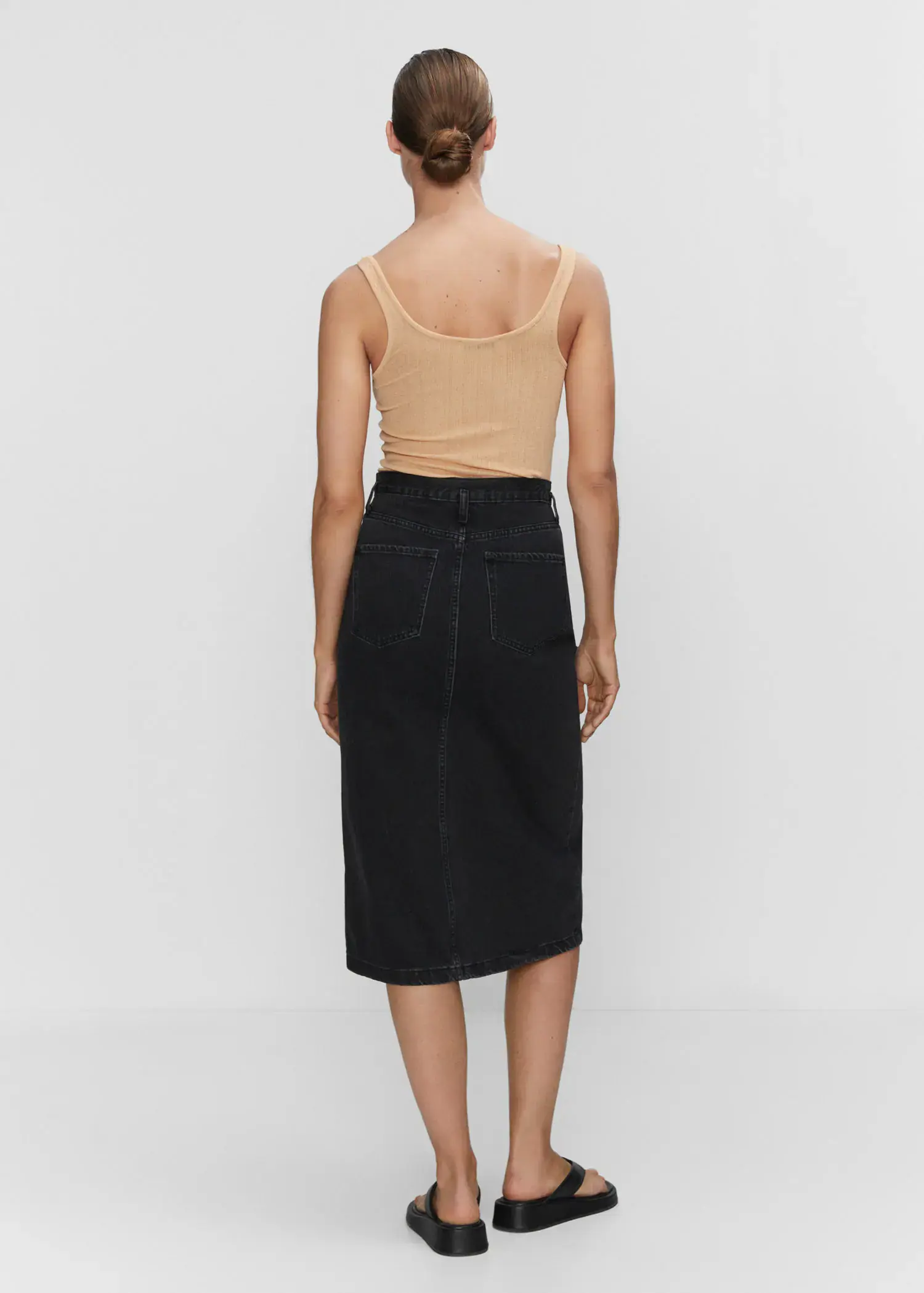 Mango Denim midi-skirt. a woman wearing a tan tank top and a black skirt. 