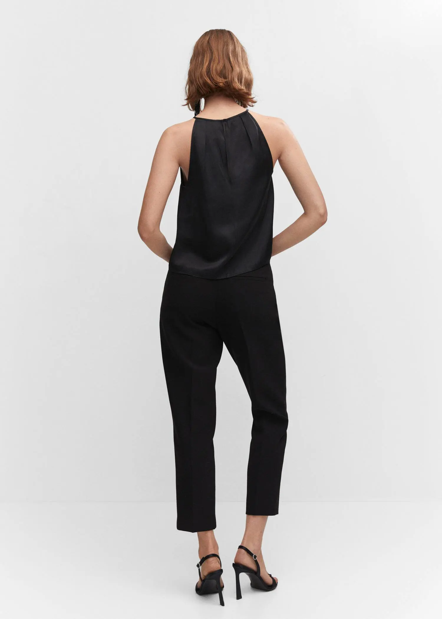 Mango Satin halter-neck top. a woman wearing a black jumpsuit standing in front of a white wall. 