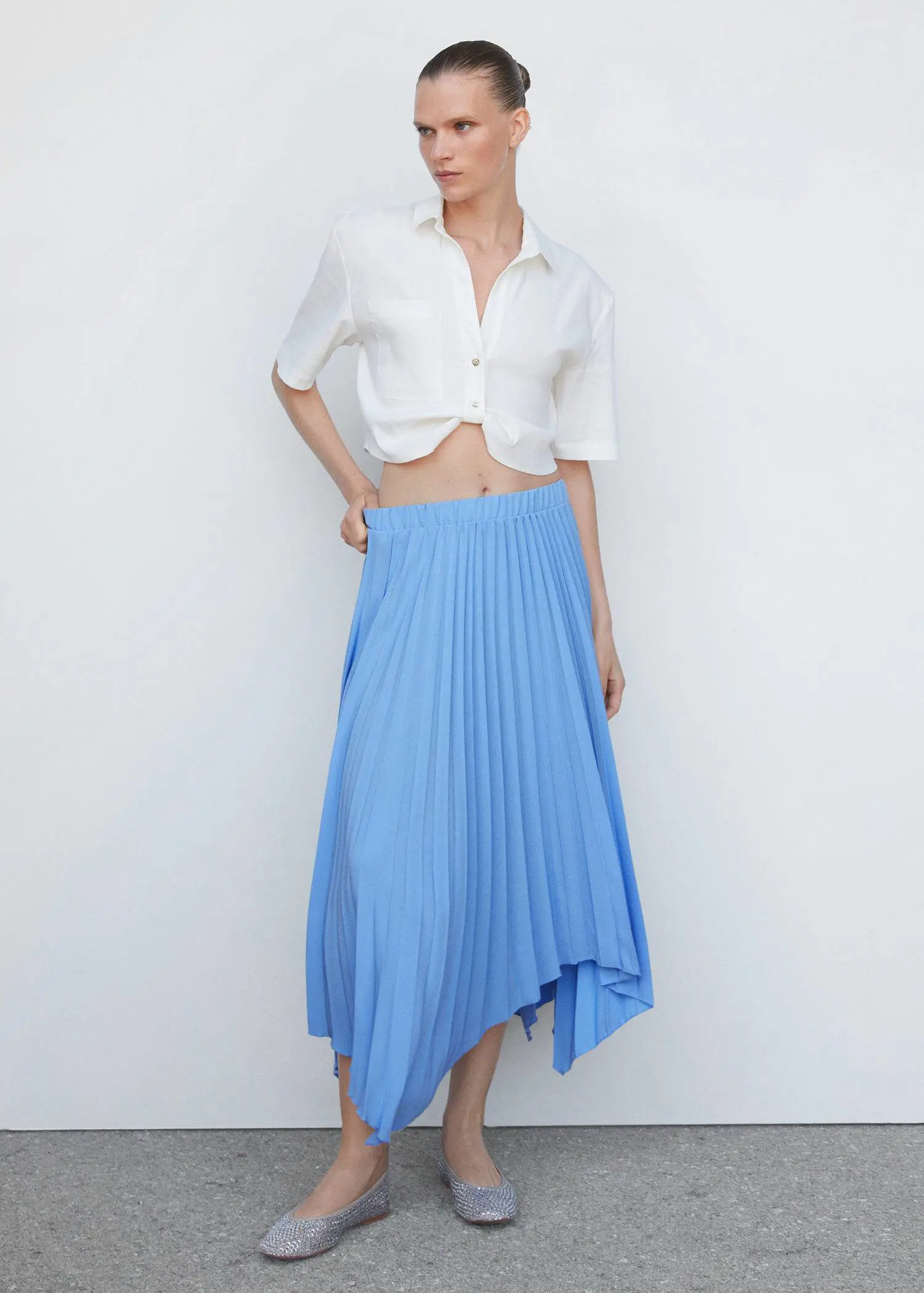 Mango Pleated asymmetric skirt . a woman wearing a white shirt and a blue skirt. 