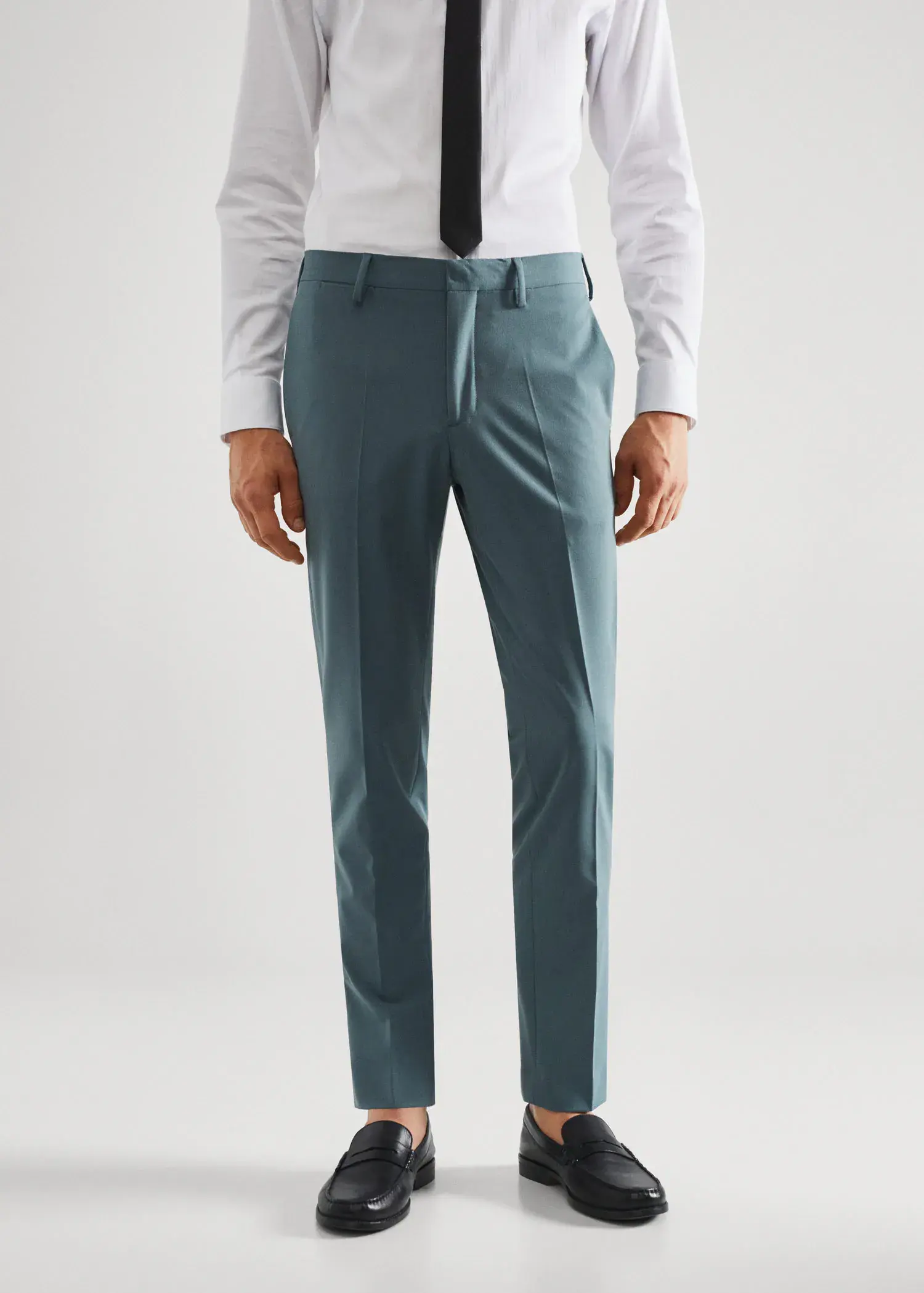 Mango Stretch fabric super slim-fit suit pants. a man wearing a suit and tie standing in front of a white wall. 