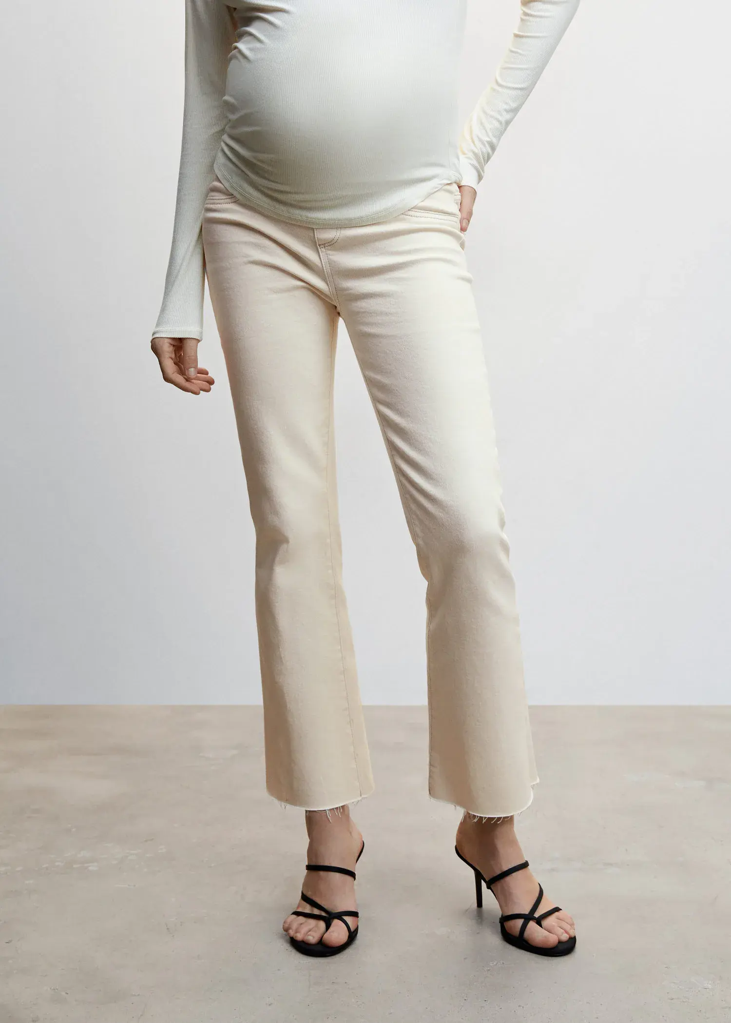 Mango Maternity flared cropped jeans. a woman standing in front of a white wall. 