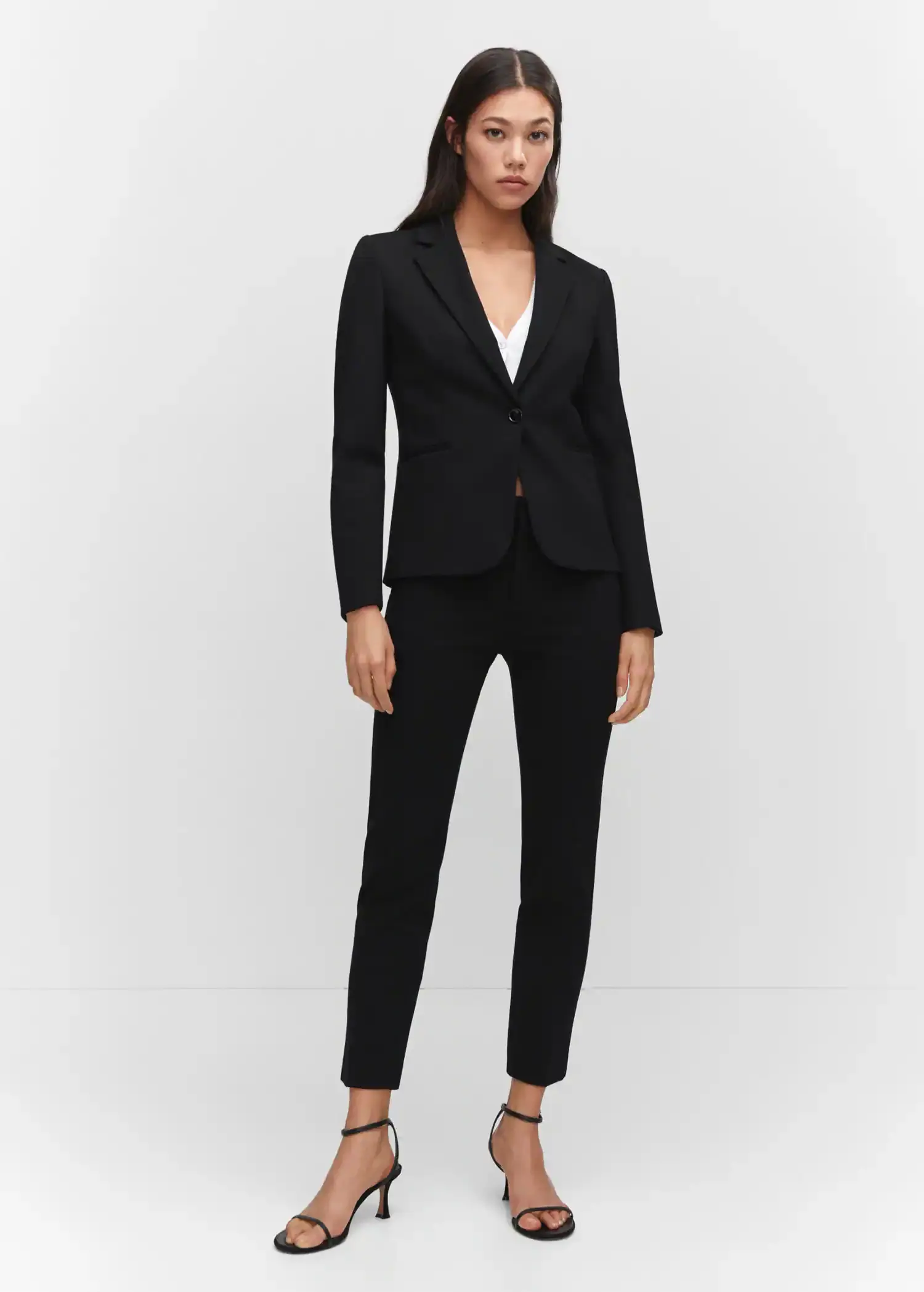 Mango Fitted jacket with blunt stitching. a woman wearing a black suit standing in front of a white wall. 