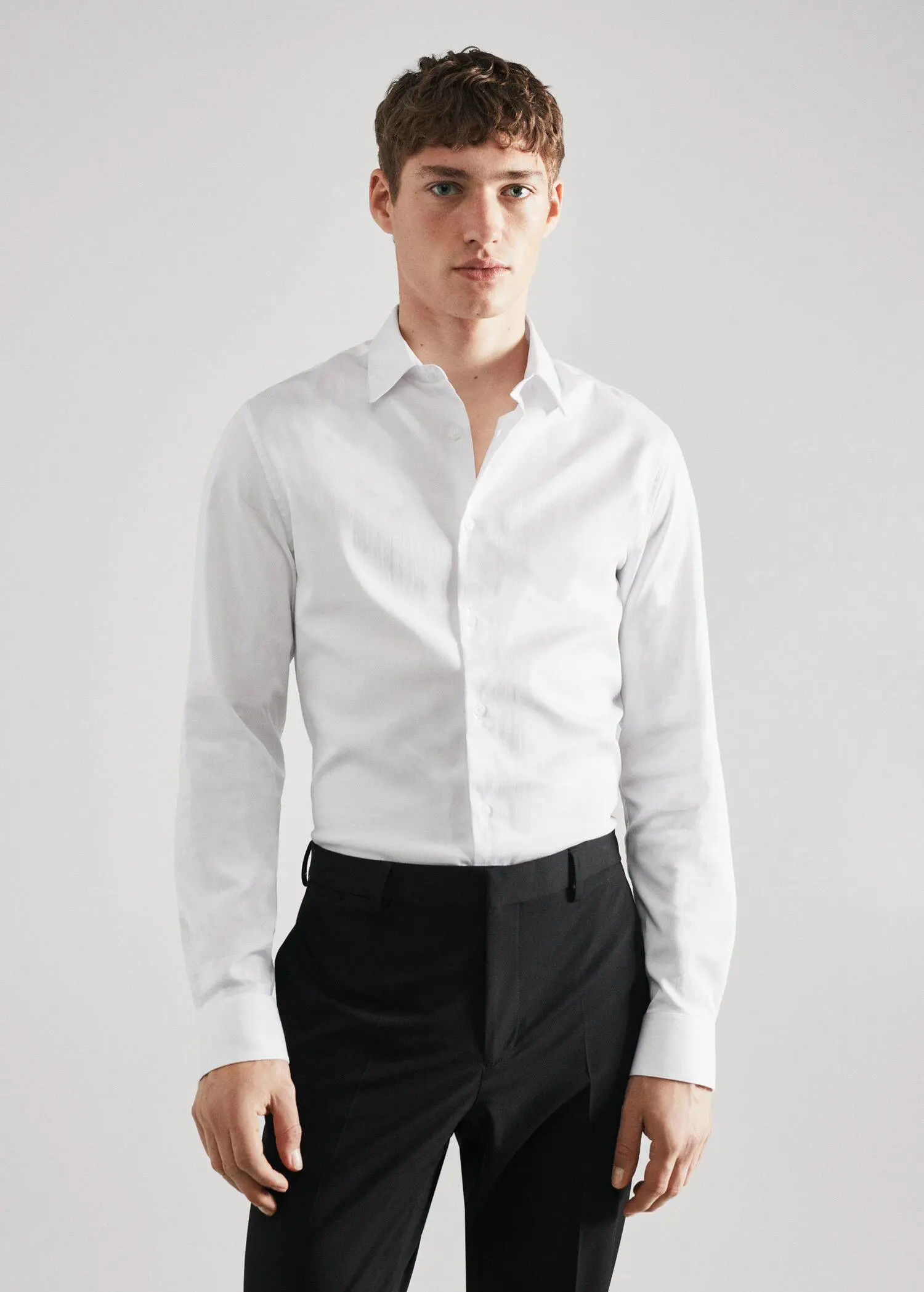 Mango Super slim-fit poplin suit shirt. a man wearing a white shirt and black pants. 