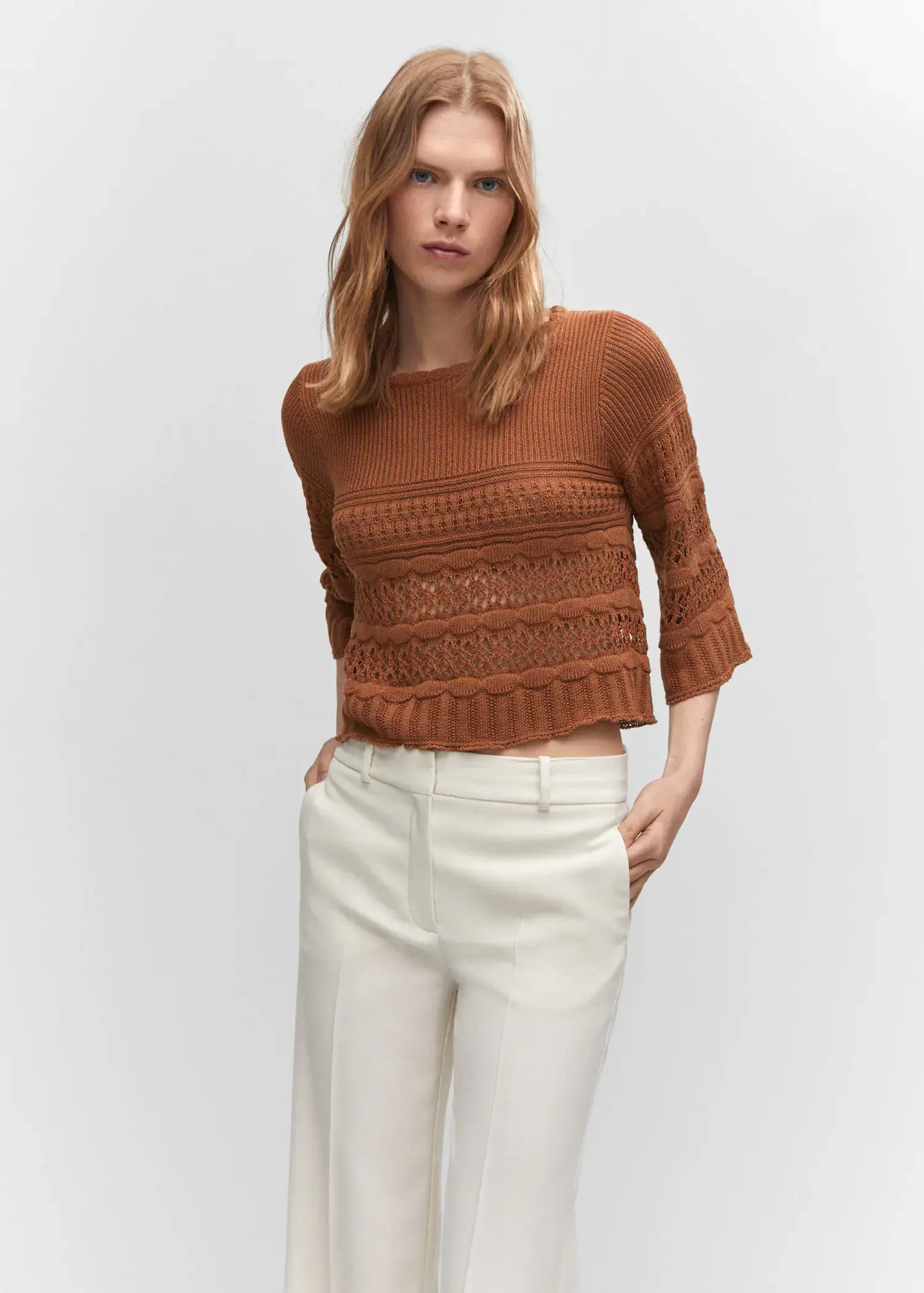 Mango Openwork sweater with flared sleeves. a woman wearing white pants and a brown sweater. 