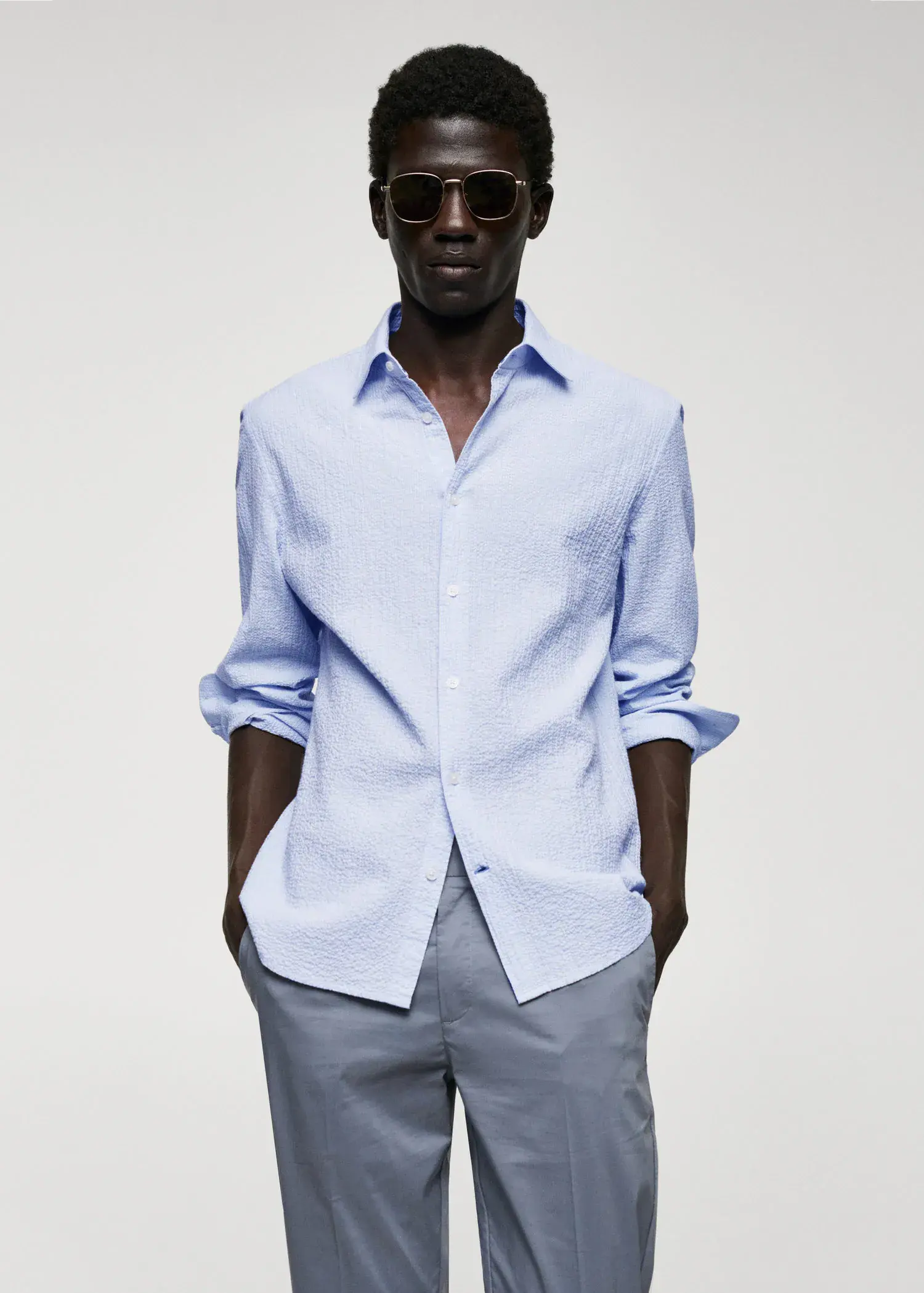 Mango Cotton seersucker shirt with multiple stripes. a man in a light blue dress shirt and grey pants. 