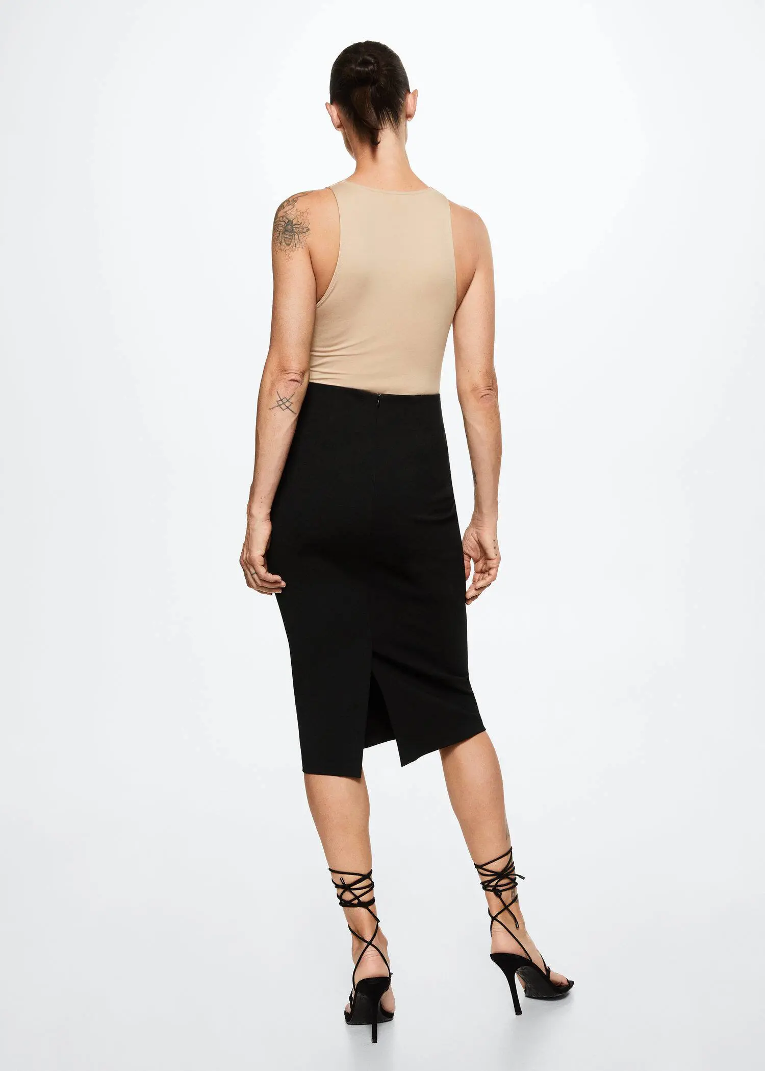 Mango Opening pencil skirt. a woman wearing a black skirt and a tan top. 