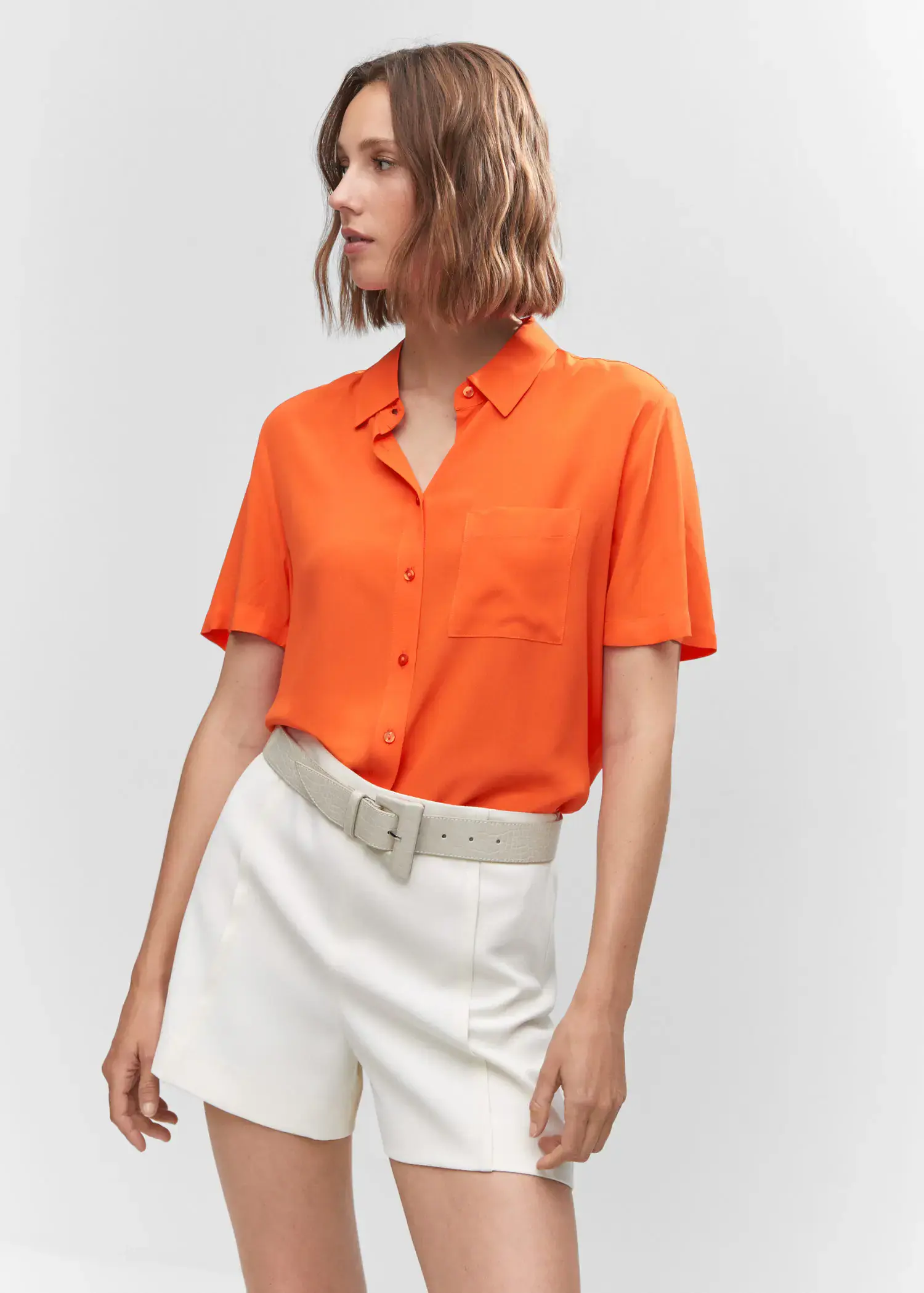 Mango Pocket oversize shirt. a woman wearing a bright orange shirt and white shorts. 