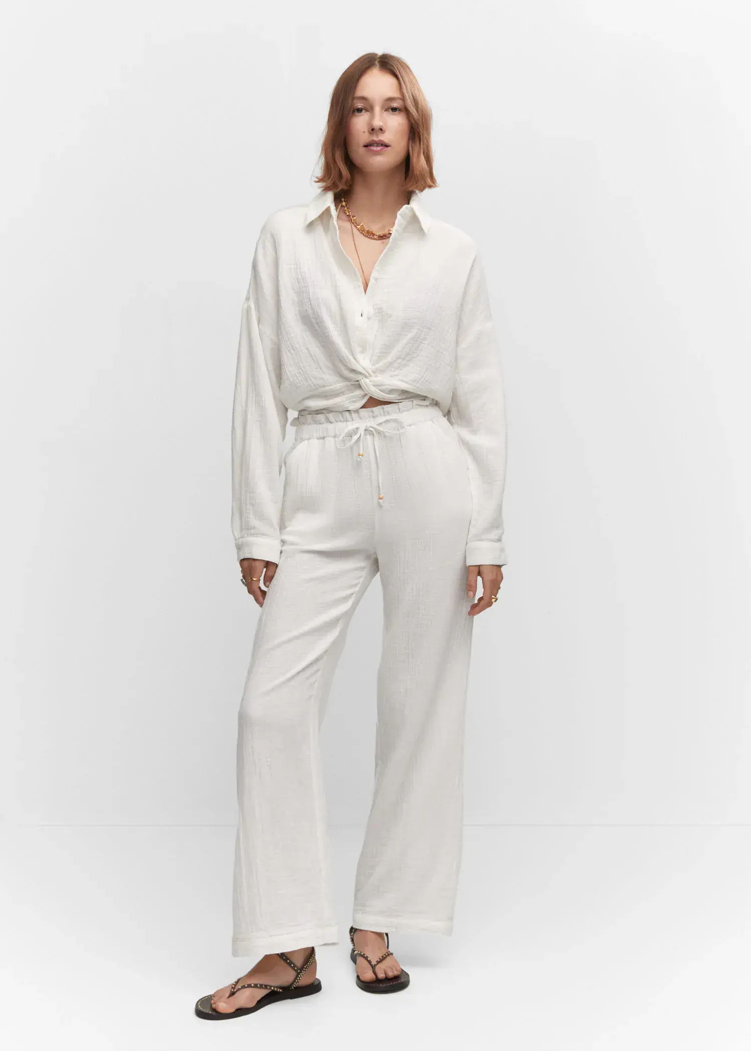 Mango Textured blouse with knot detail. a woman in a white outfit standing in front of a white wall. 