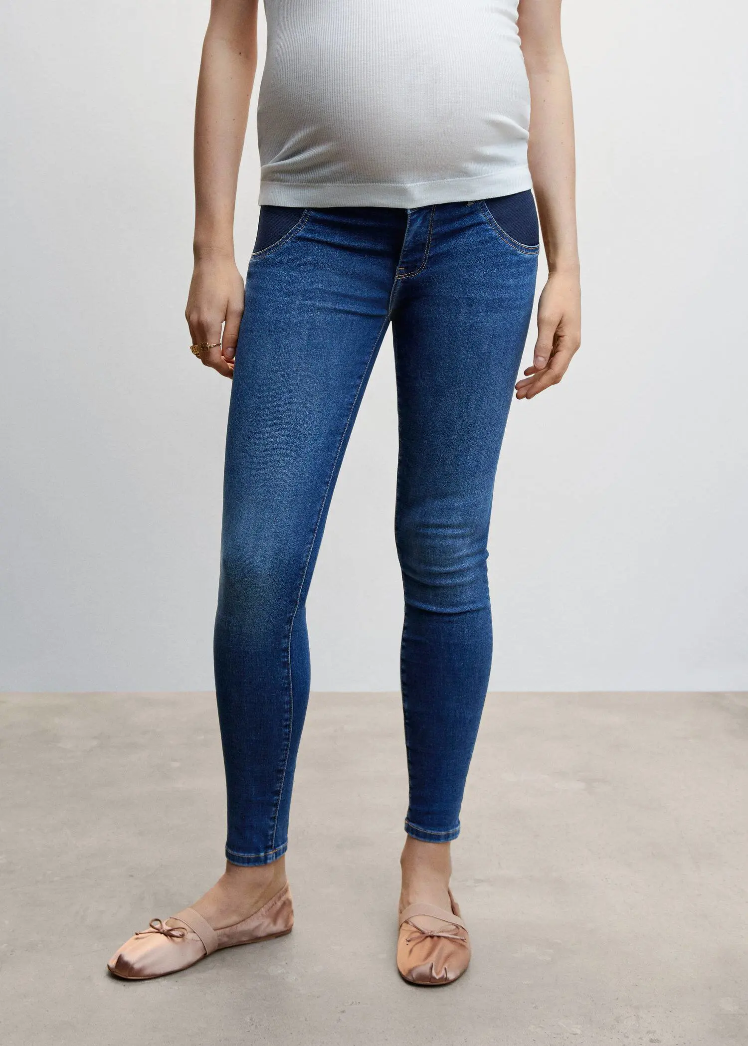 Mango Maternity skinny jeans. a woman standing with her legs crossed wearing jeans. 