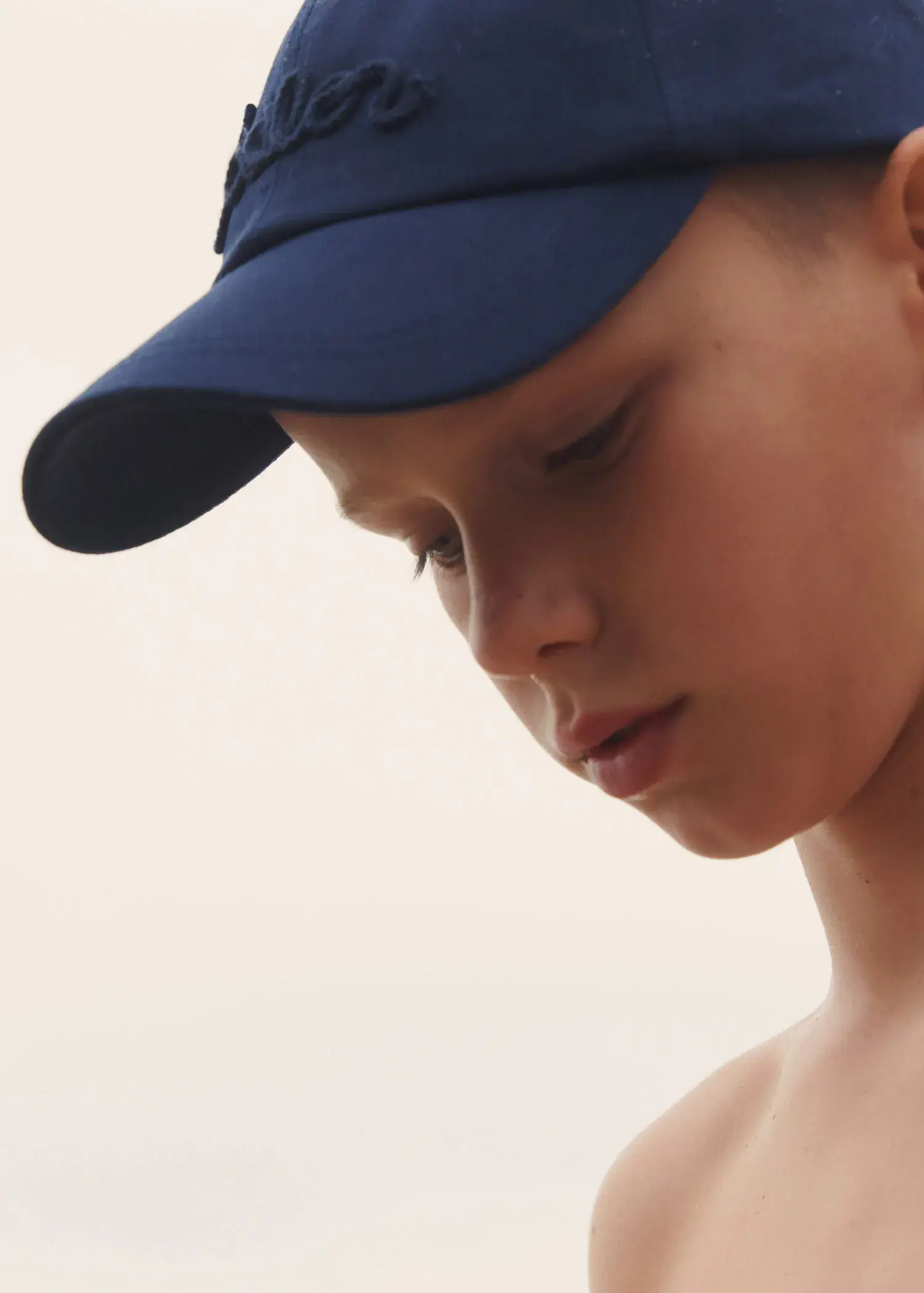Mango  KIDS/ Embroidered cotton cap. a young boy wearing a baseball cap looking to his left. 