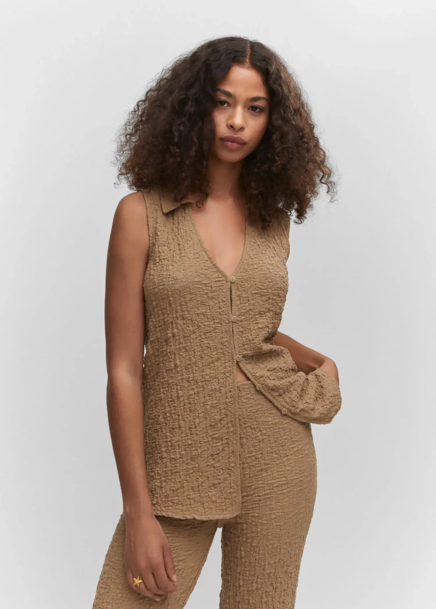 Mango Textured polo neck vest. a woman in a tan outfit standing in front of a white wall. 