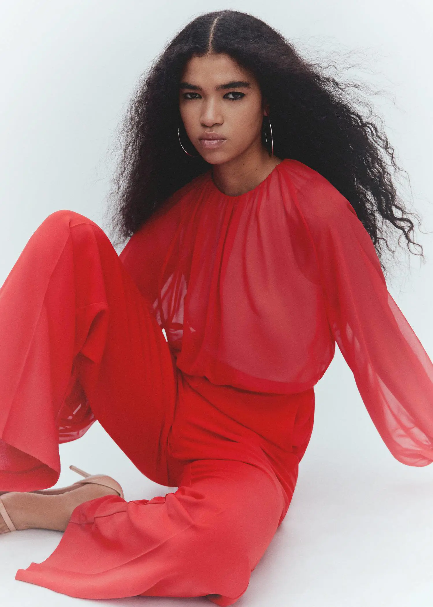 Mango Semi-transparent chiffon jumpsuit. a woman in a red outfit sitting on the ground. 