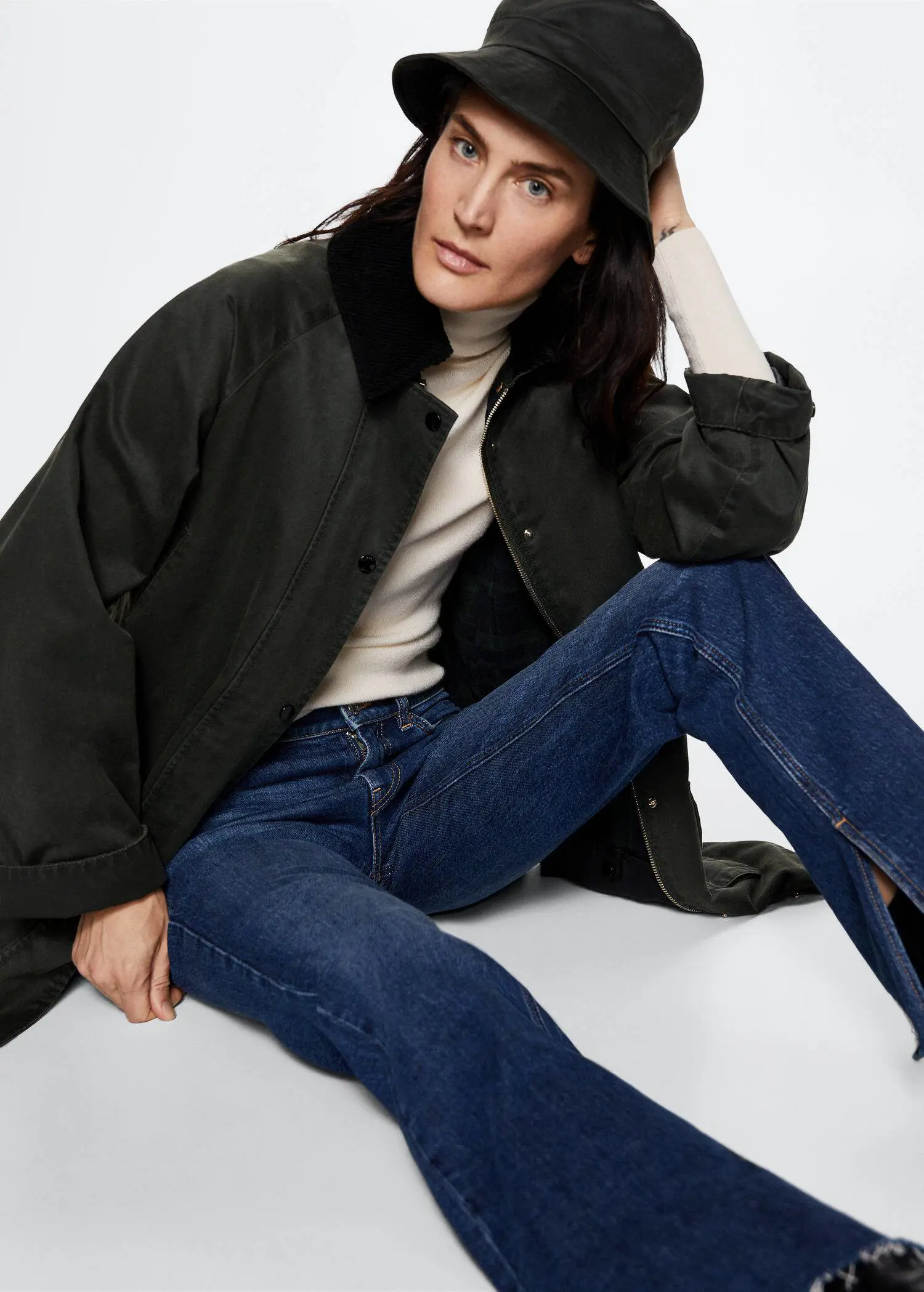 Mango Waxed-effect parka. a woman sitting on the ground wearing jeans and boots. 