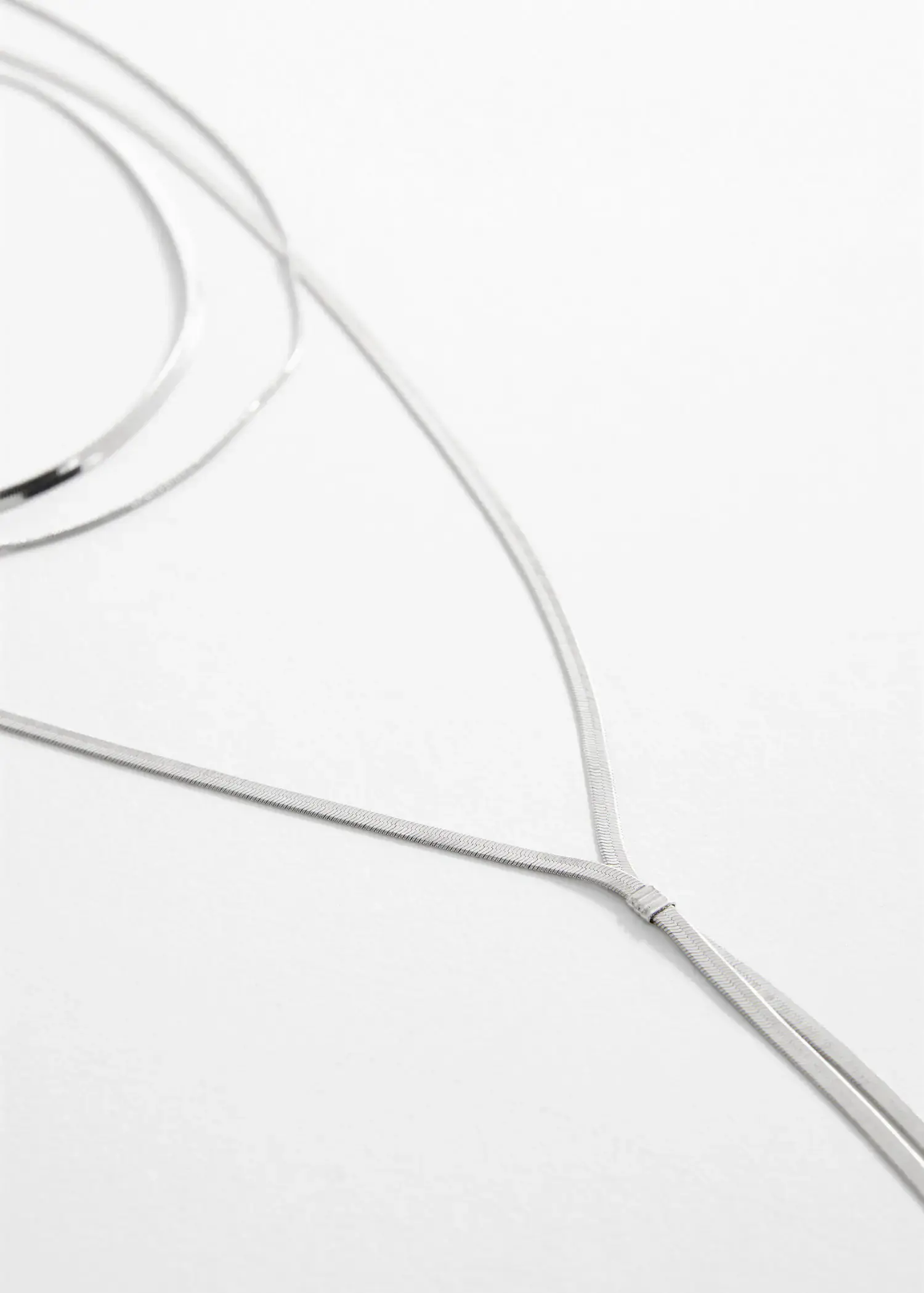Mango Long triple necklace. a close-up of a long white necklace on a table. 