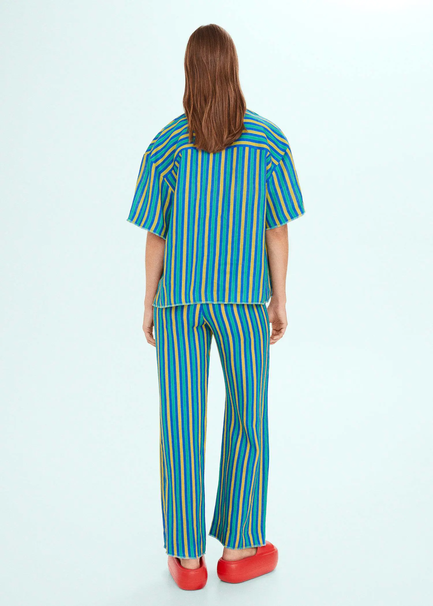 Mango Multi-coloured striped linen trousers. a person standing in front of a blue wall. 
