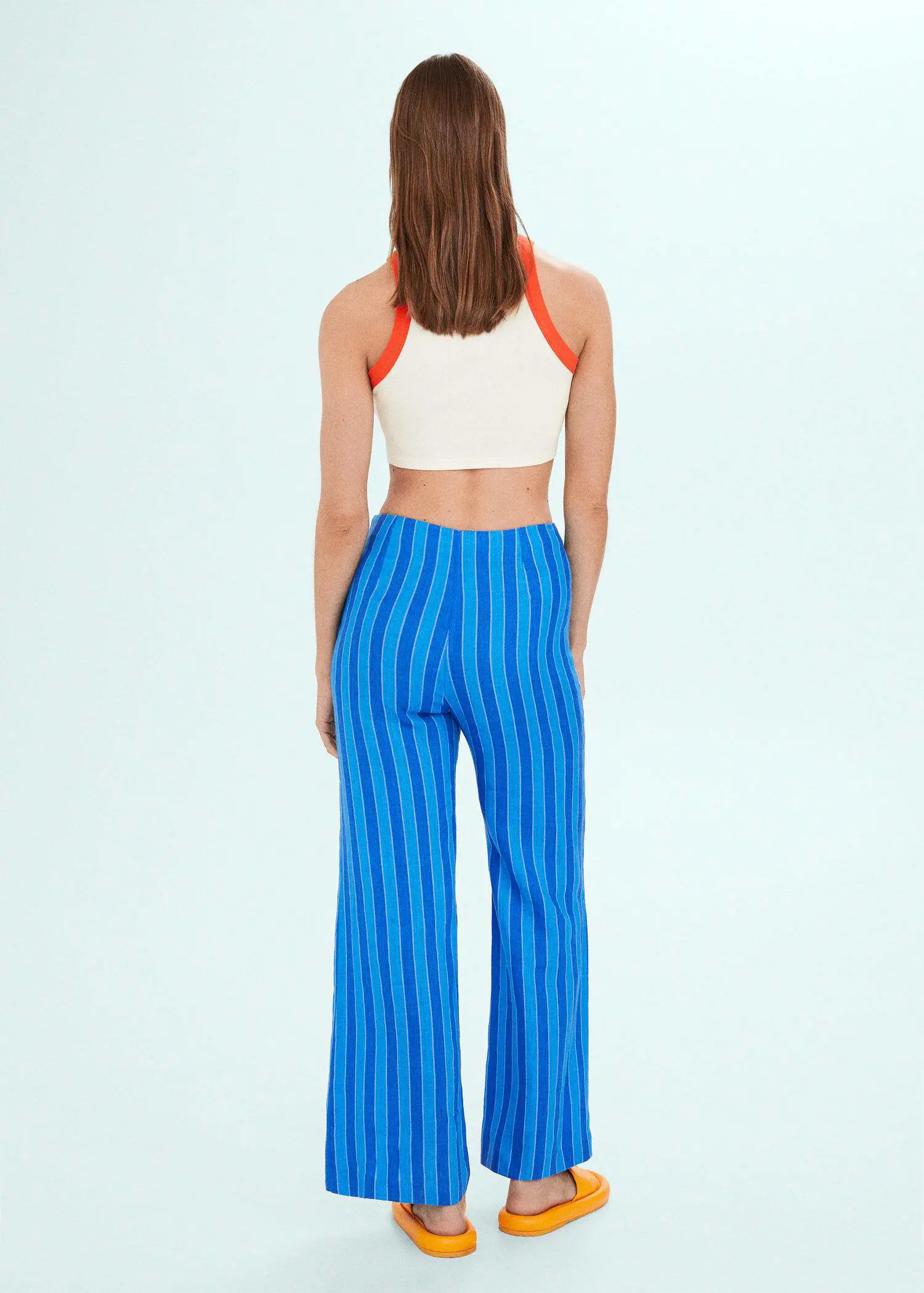 Mango Printed halter-neck cropped top. a woman wearing a white crop top and blue pants. 