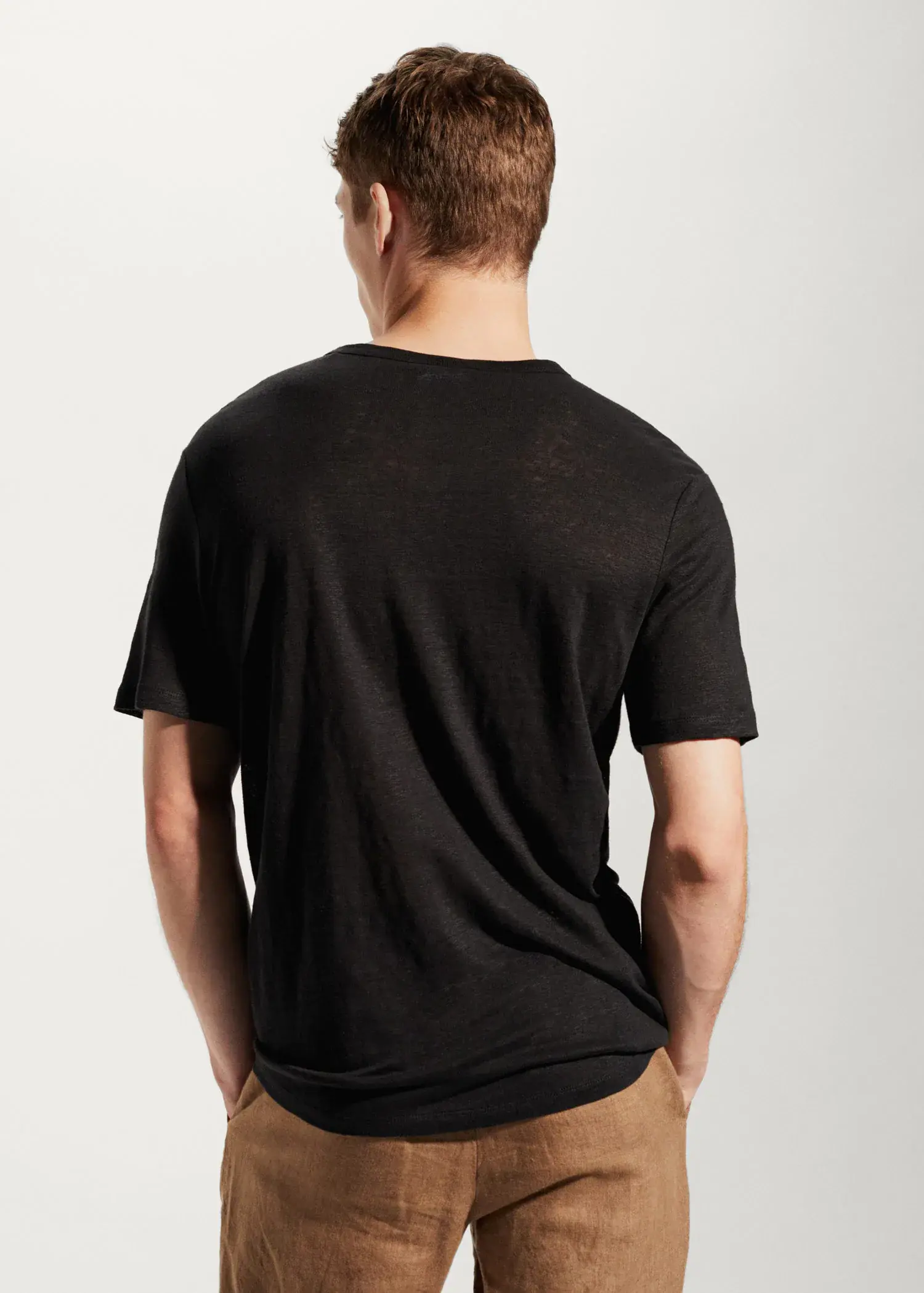 Mango 100% linen Henley t-shirt. a man in a black shirt is standing up 