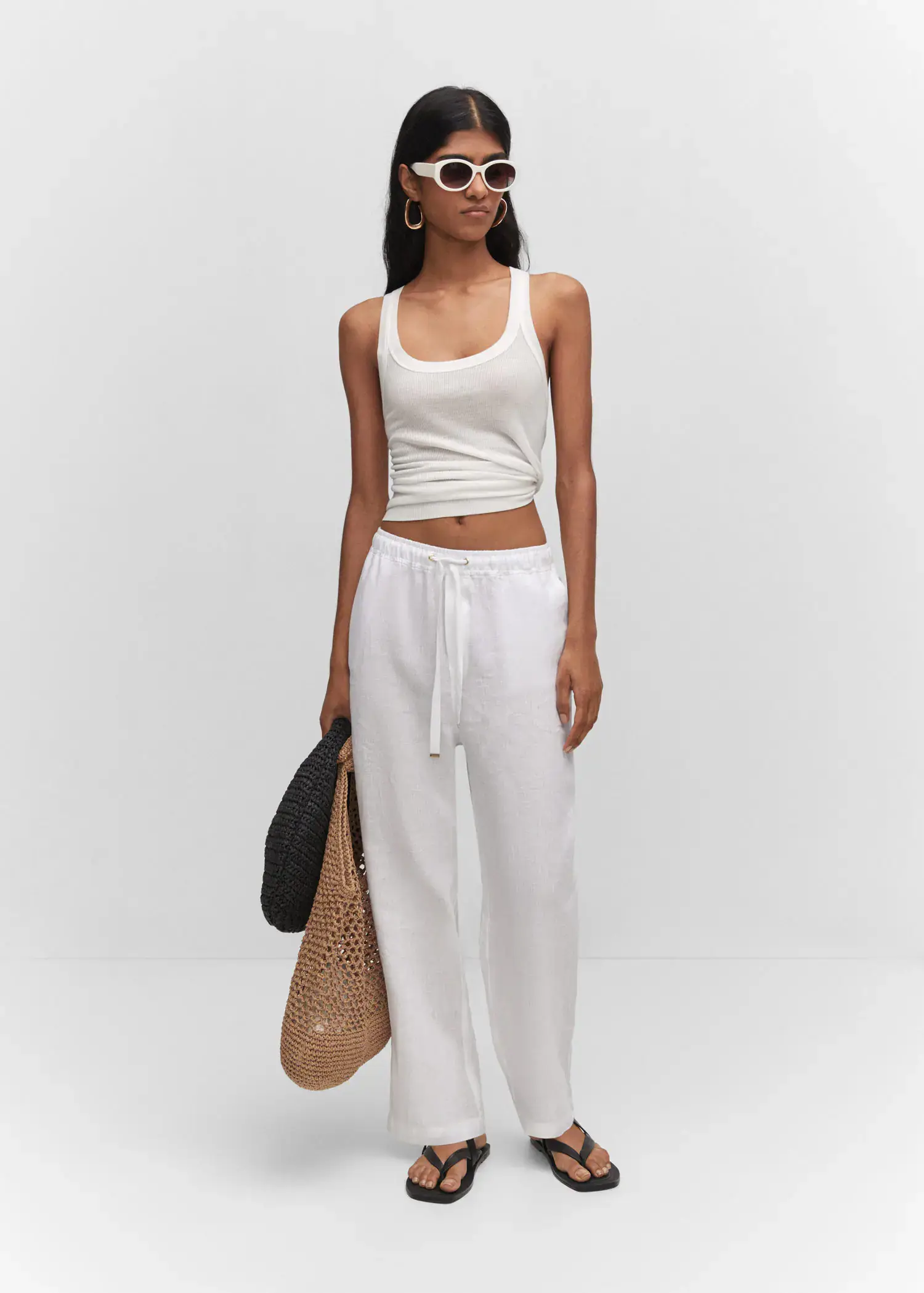 Mango Bow linen pants. a woman in a white outfit holding a straw bag. 