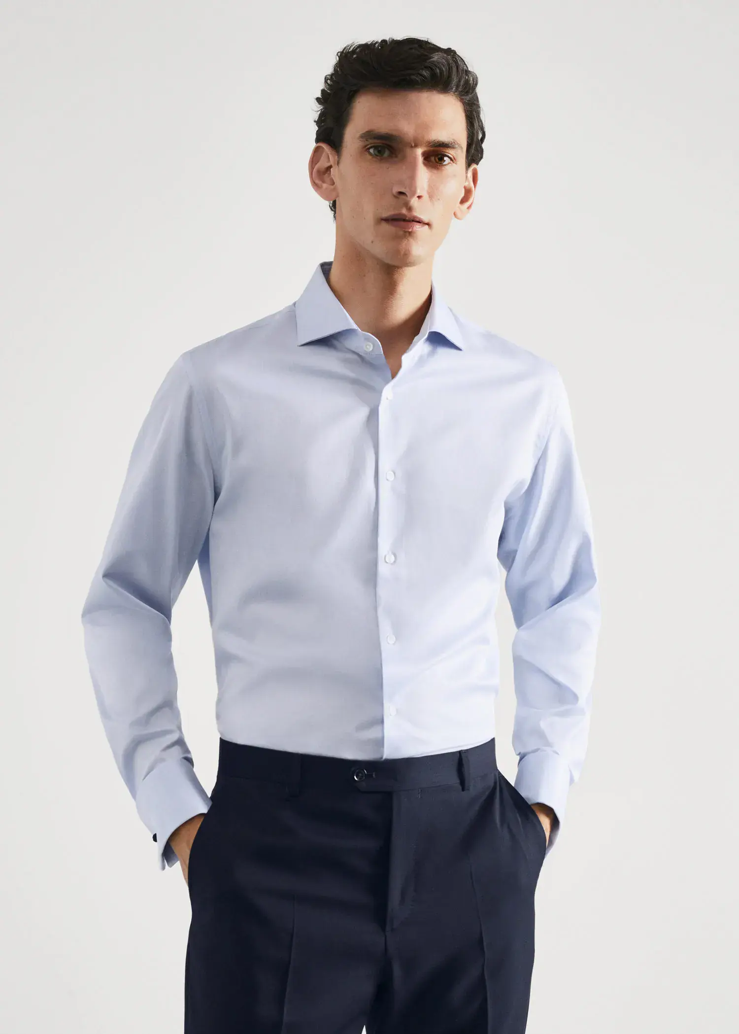 Mango Twill fabric slim-fit suit shirt with cufflinks . a man wearing a light blue dress shirt and black pants. 